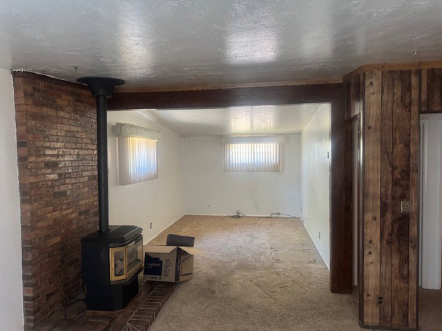 Living area featuring a brick accent wall, wood-burning stove, and wood-paneled detailing