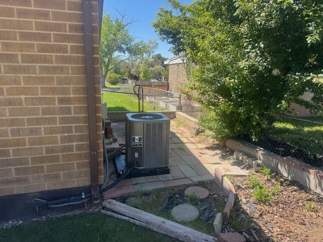 Brick exterior with an outdoor HVAC unit, paver patio, and garden beds