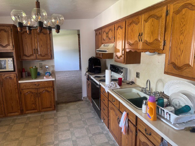 Kitchen featuring wood cabinetry, laminate countertops, and a double basin sink