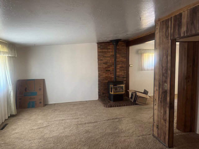 Spacious interior featuring a brick-clad wood-burning stove with a hearth, complemented by wood-paneled walls