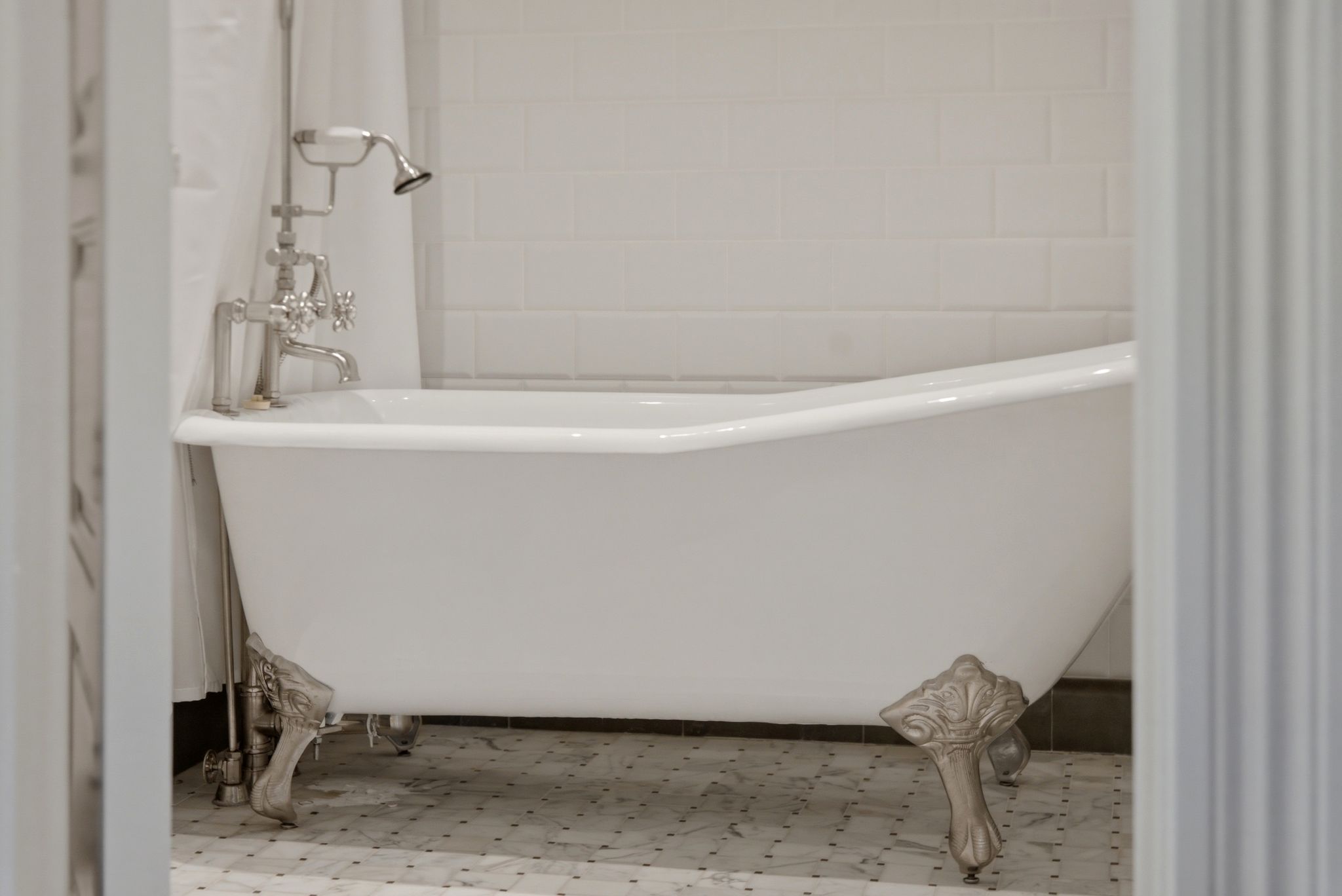 Freestanding clawfoot bathtub featuring polished chrome fixtures and a handheld shower