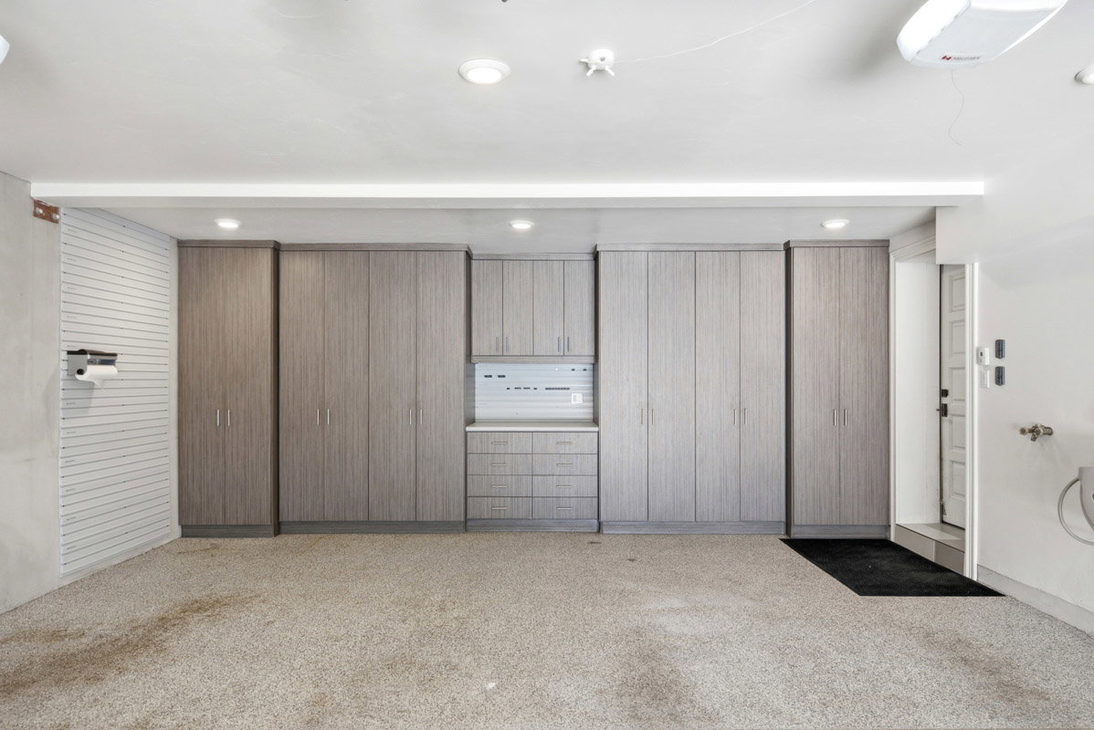 Integrated garage storage system featuring multiple full-height cabinets, base cabinets with drawers, and upper cabinetry