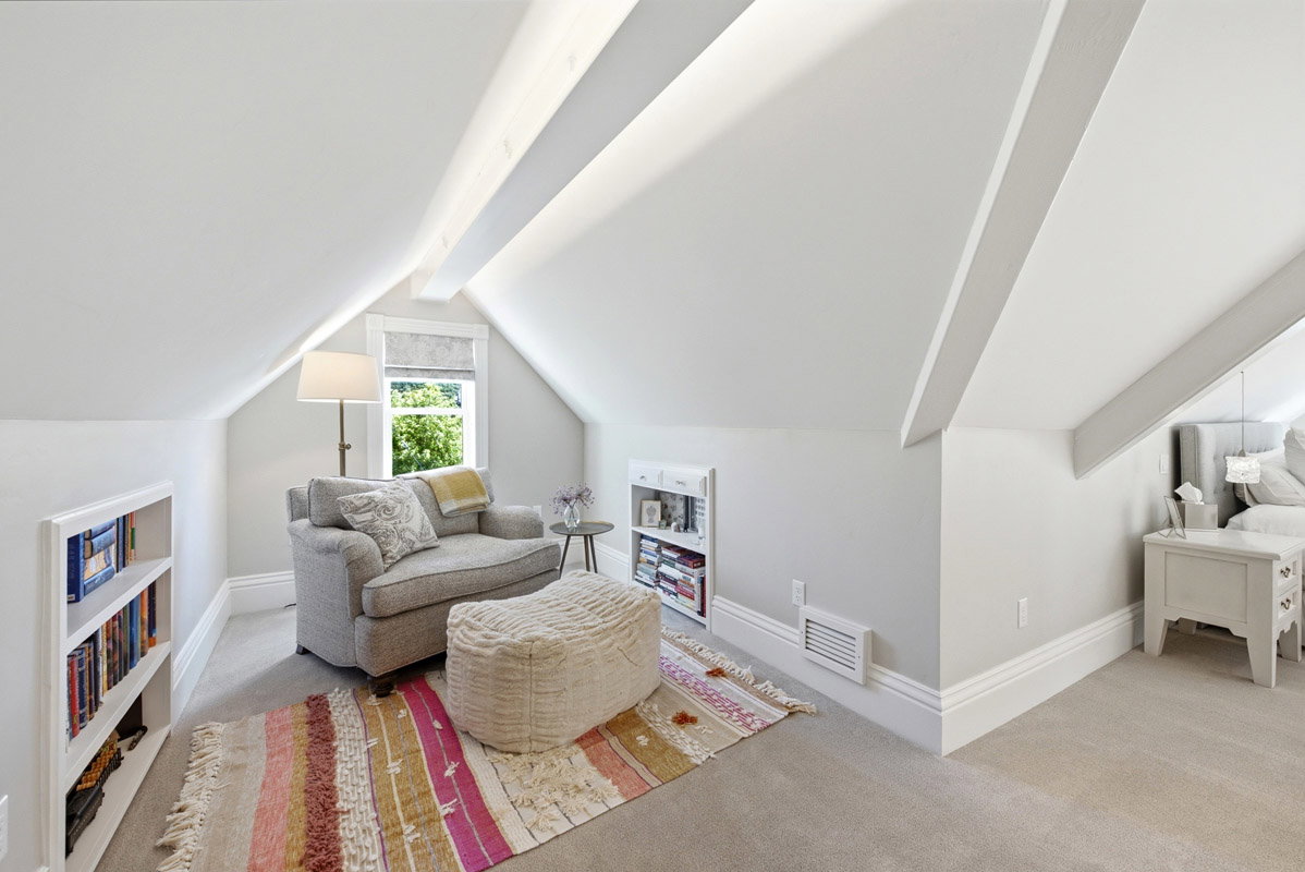 Gable roofline with exposed beams, built-in shelving, window with natural light, and neutral wall finishes