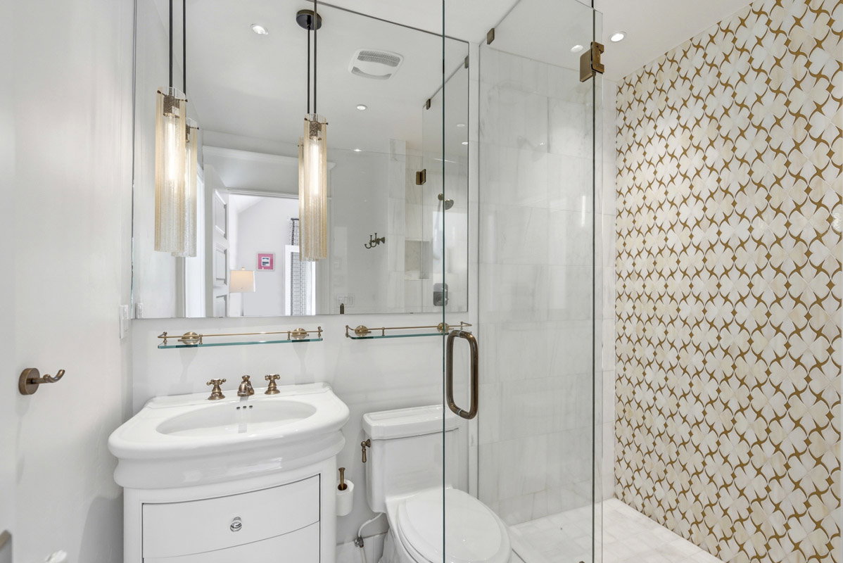 Bathroom featuring a glass-enclosed shower, decorative wall tiling, pedestal sink, and pendant lighting fixtures
