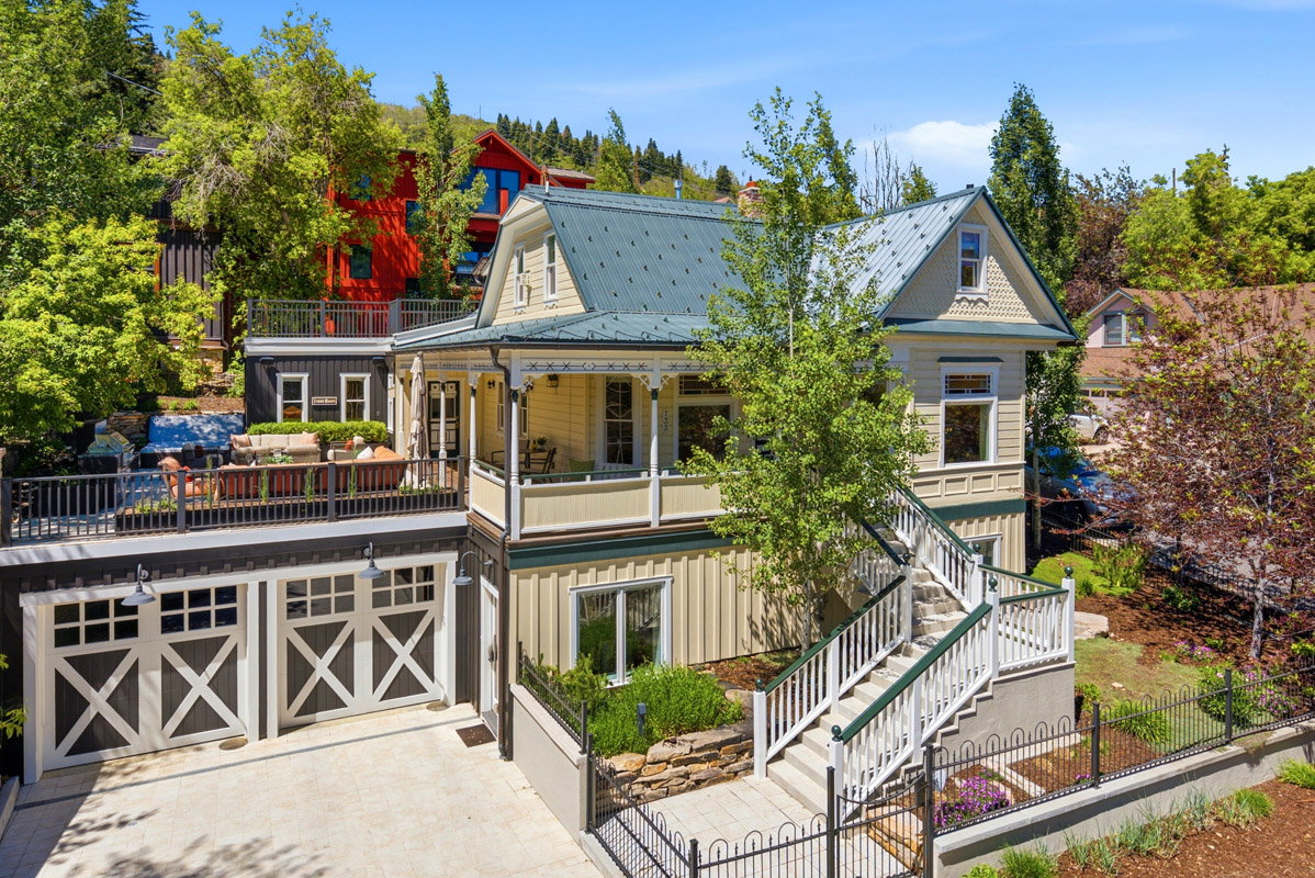 Victorian-inspired residence featuring a covered front porch, an upper-level patio, and a two-car garage with carriage-style doors