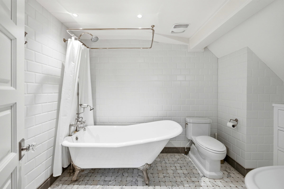 Clawfoot tub with polished chrome fixtures, white subway tile walls, and mosaic tile flooring