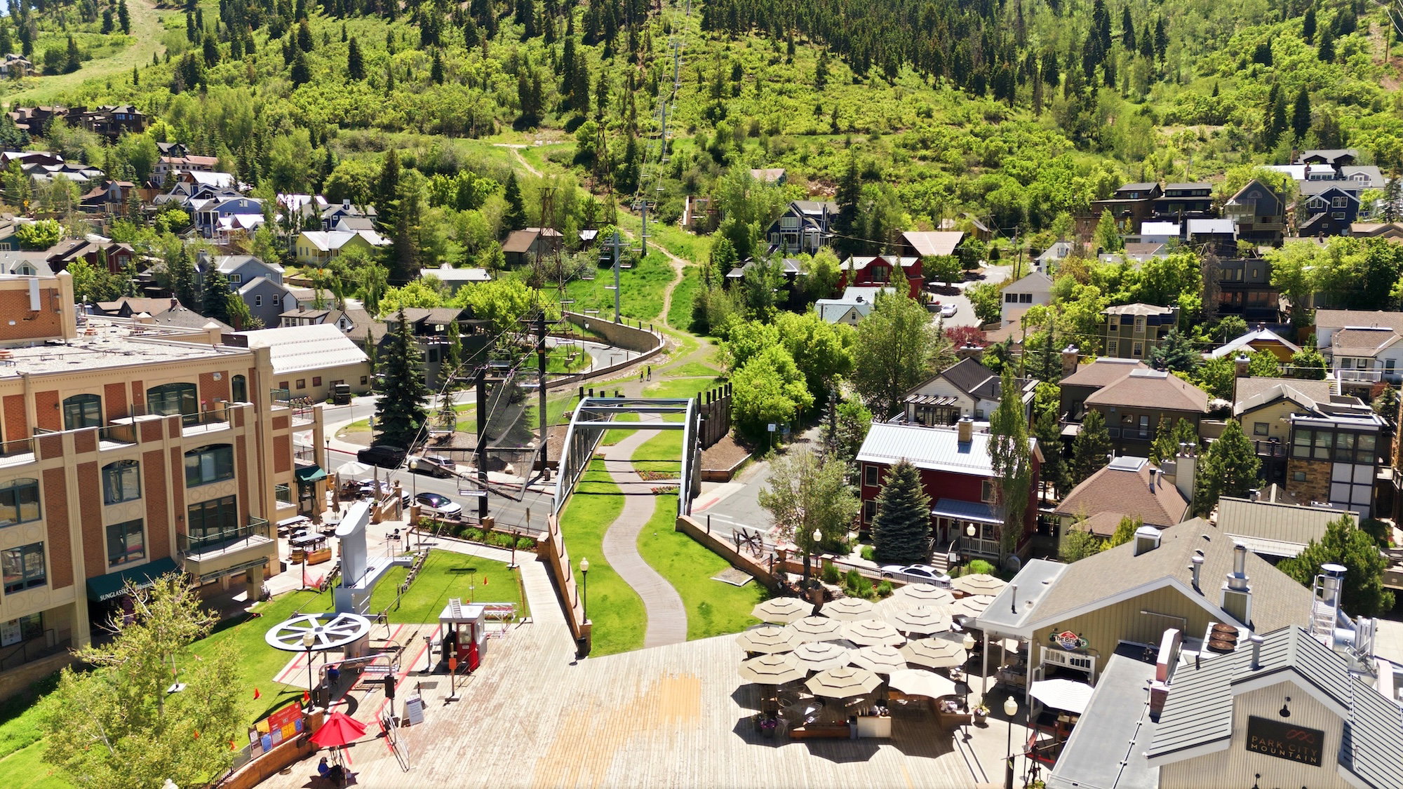 Townscape featuring a mix of residential and commercial buildings, lush green hillsides, and a pedestrian pathway