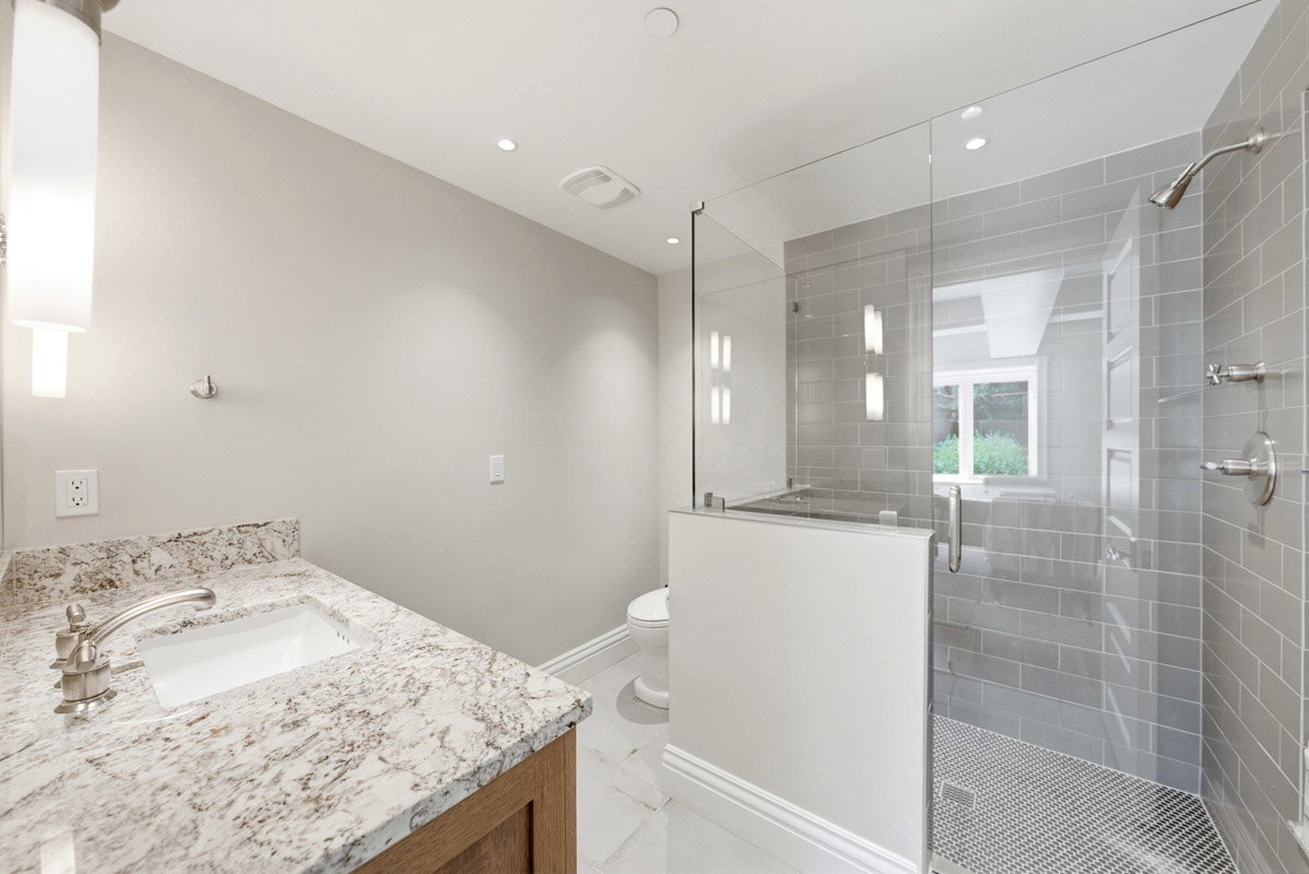Modern bathroom featuring a wood-finish vanity with a granite countertop, undermount sink, and brushed nickel fixtures
