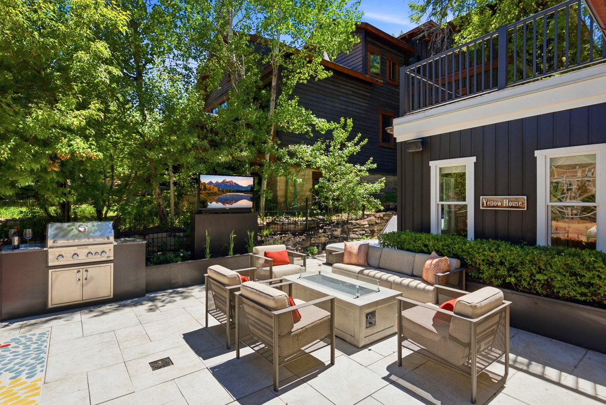 Spacious patio featuring paver flooring, an outdoor kitchen with built-in grill, a fire pit, and a mounted outdoor television