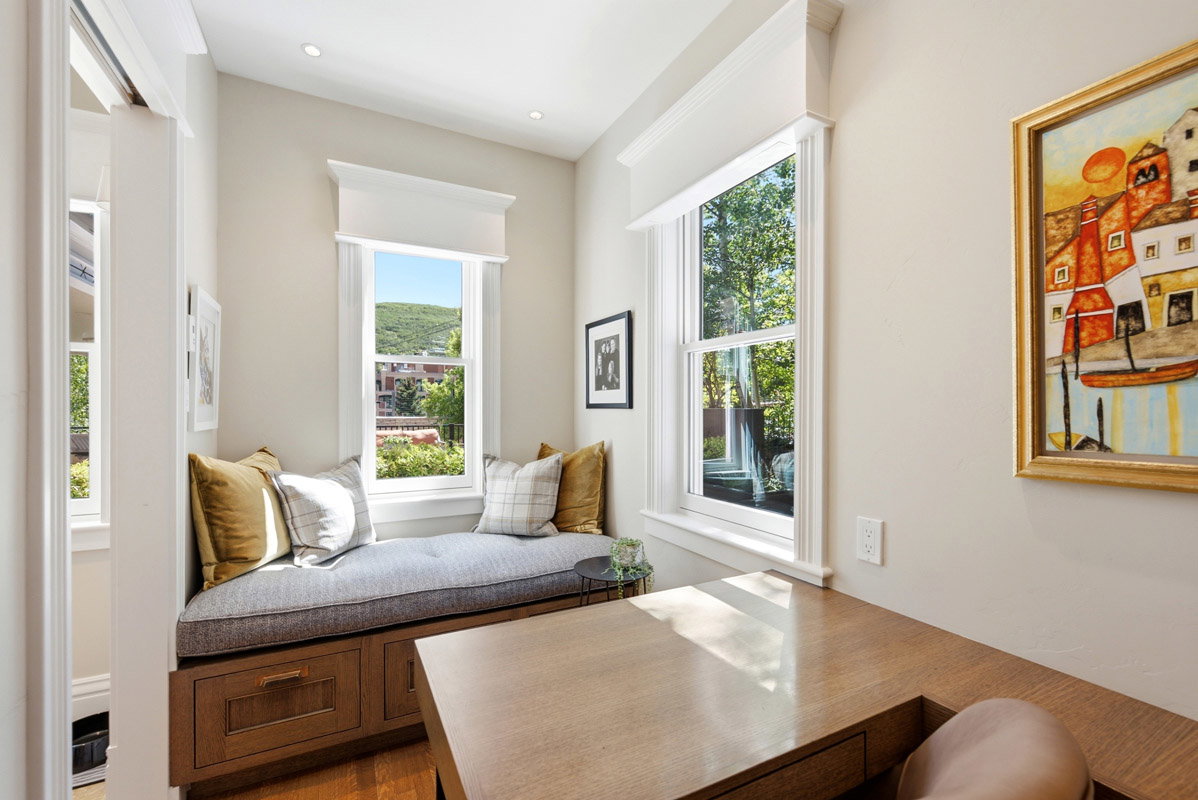 Integrated window seat with built-in storage drawers, double-hung windows, recessed lighting, and light wood-finish built-in desk