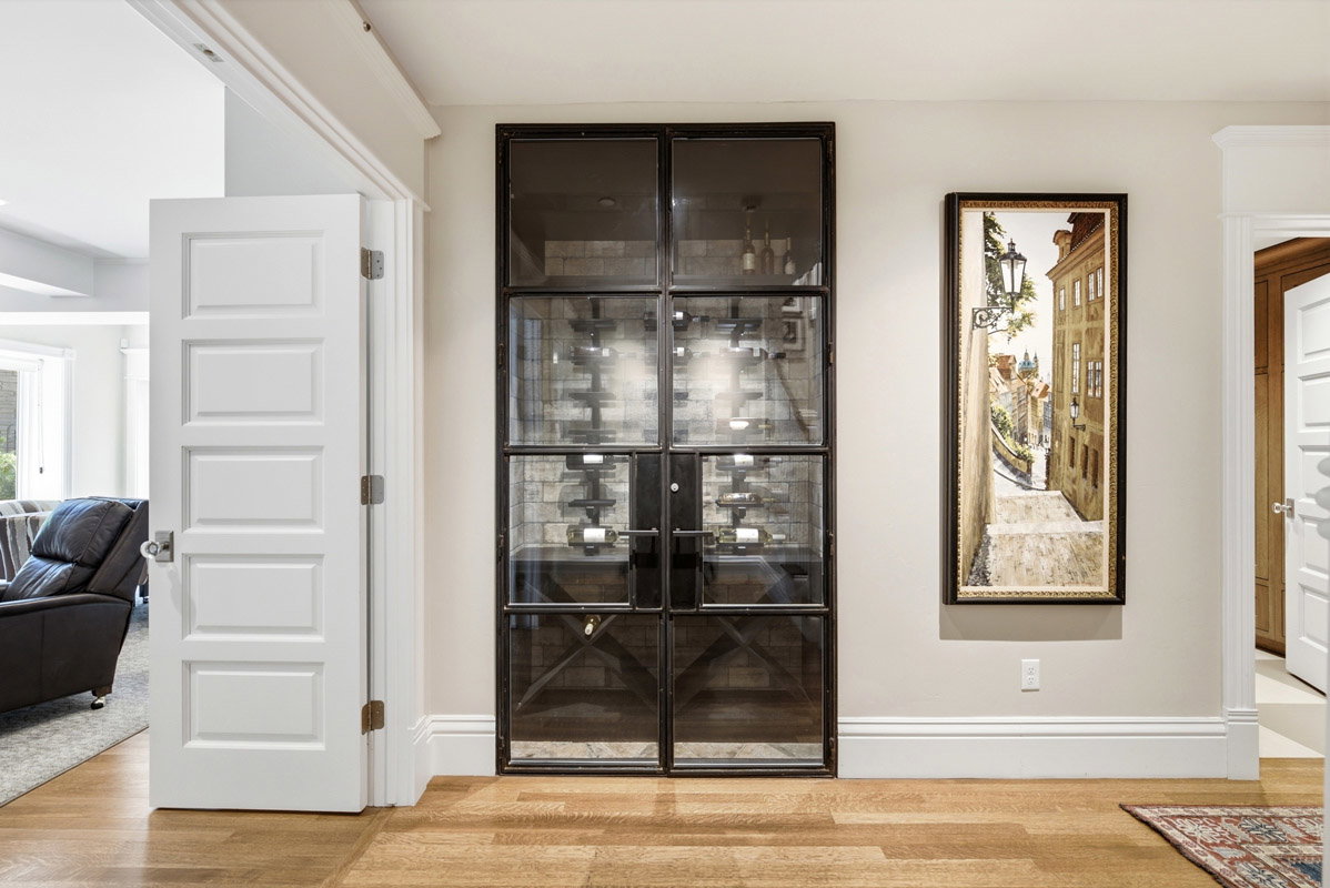 Custom wine cellar with glass and metal doors, featuring interior brick-style wall treatment and built-in bottle racks