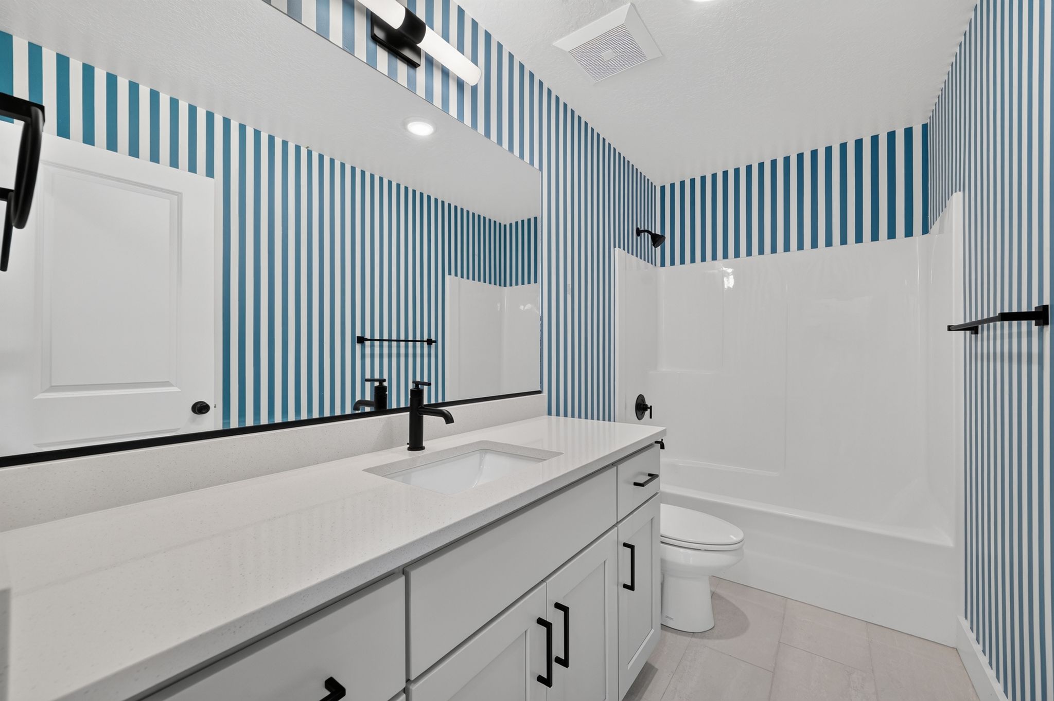 Bathroom vanity featuring a quartz countertop, integrated sink, and matte black fixtures