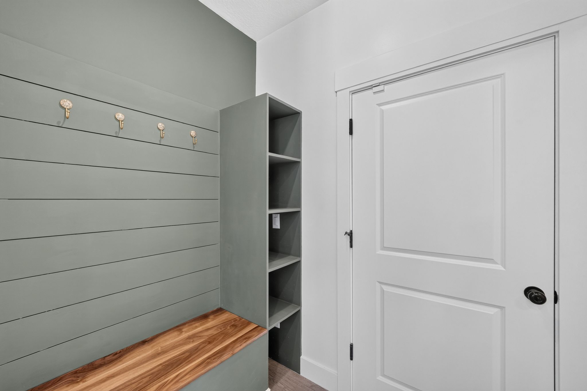 Mudroom featuring shiplap wall paneling, built-in bench with wood surface, custom shelving unit, and decorative wall hooks