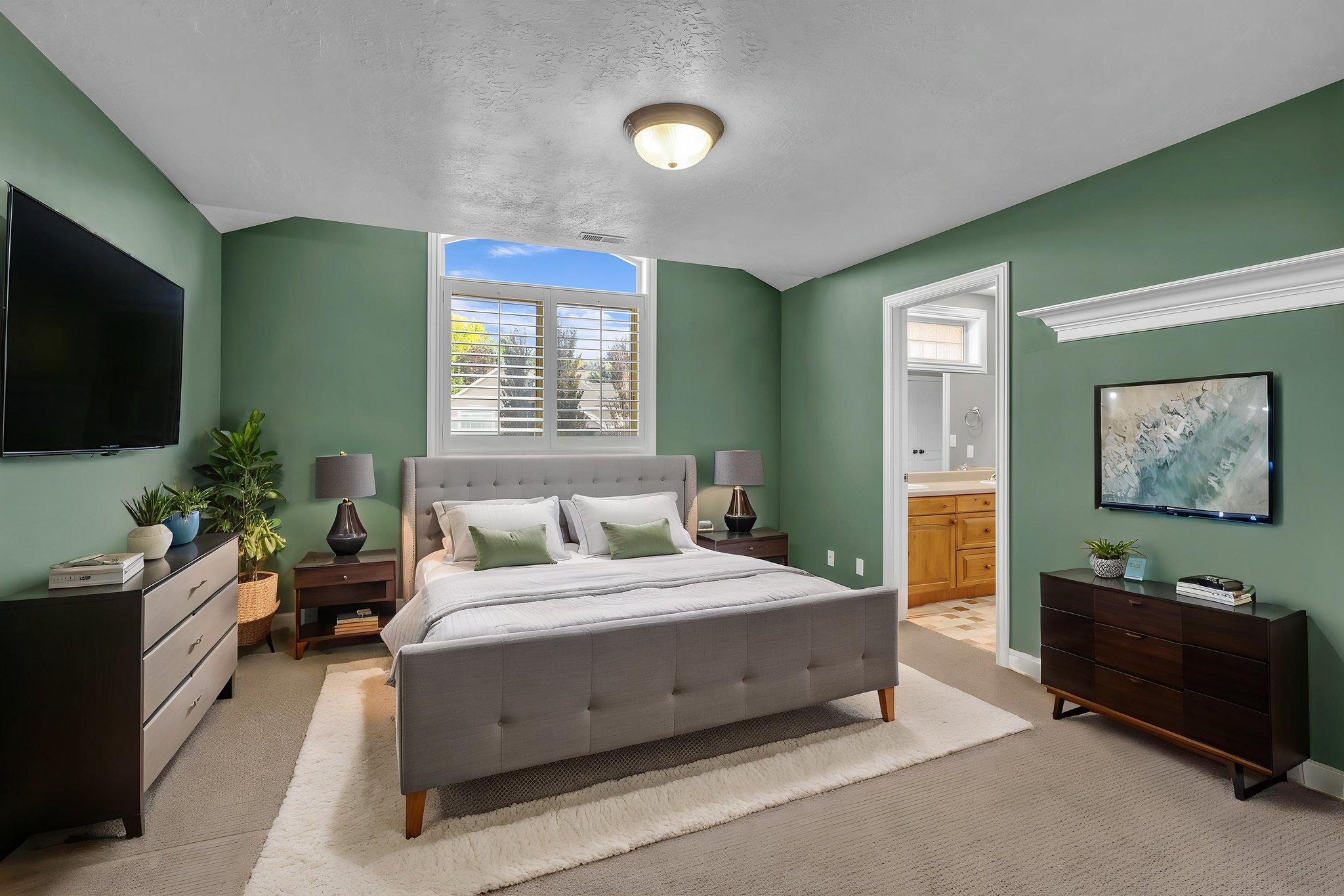 Bedroom featuring a large double window with plantation shutters, neutral carpeting, and an arched doorway leading to an additional space