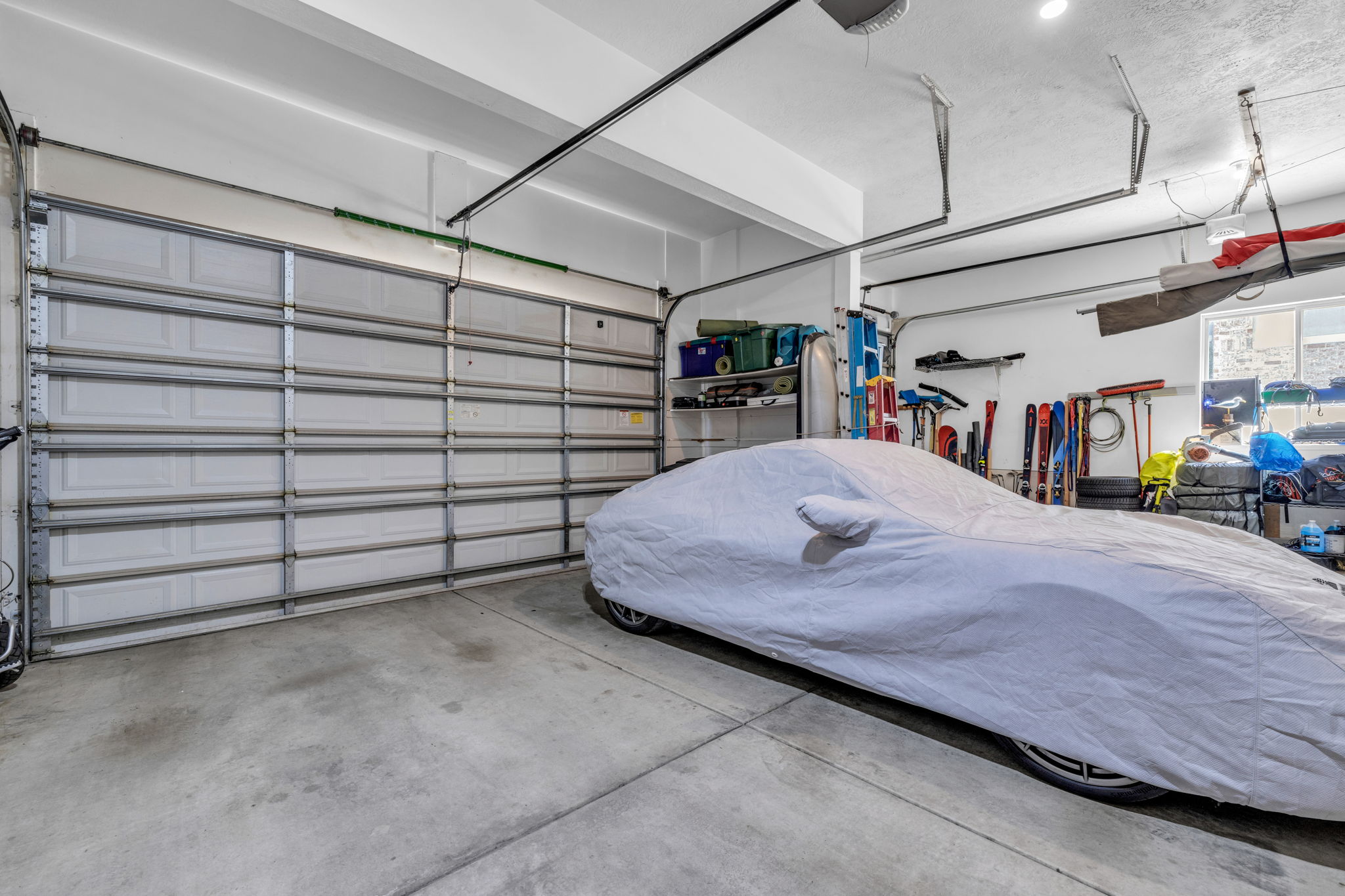 Spacious garage featuring a large sectional overhead door, concrete flooring, and ample storage space with visible shelving