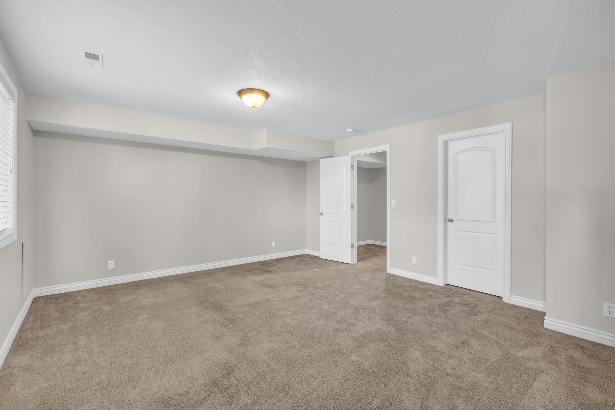 Spacious room with plush carpeting, neutral wall finishes, white trim, and two paneled doors
