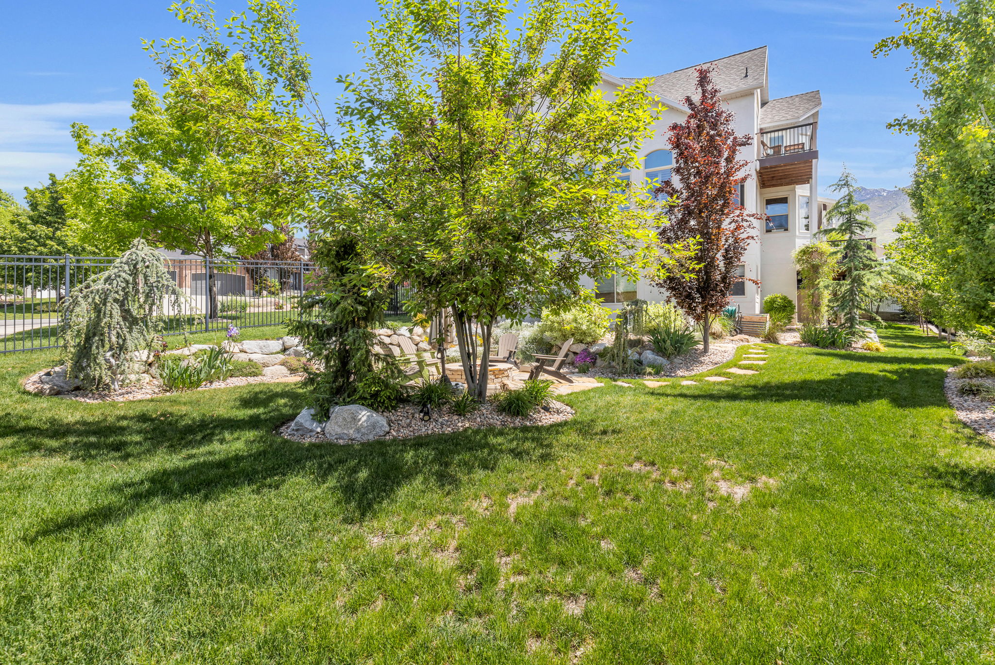 Expansive green lawn with established trees and layered landscaping