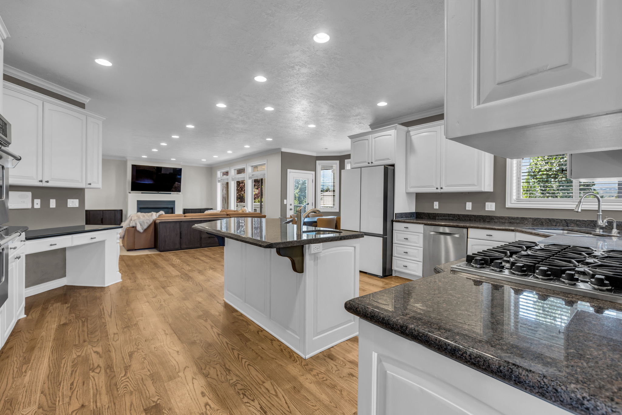 Kitchen featuring white shaker cabinetry, dark granite countertops, stainless steel appliances, and wood-finish flooring