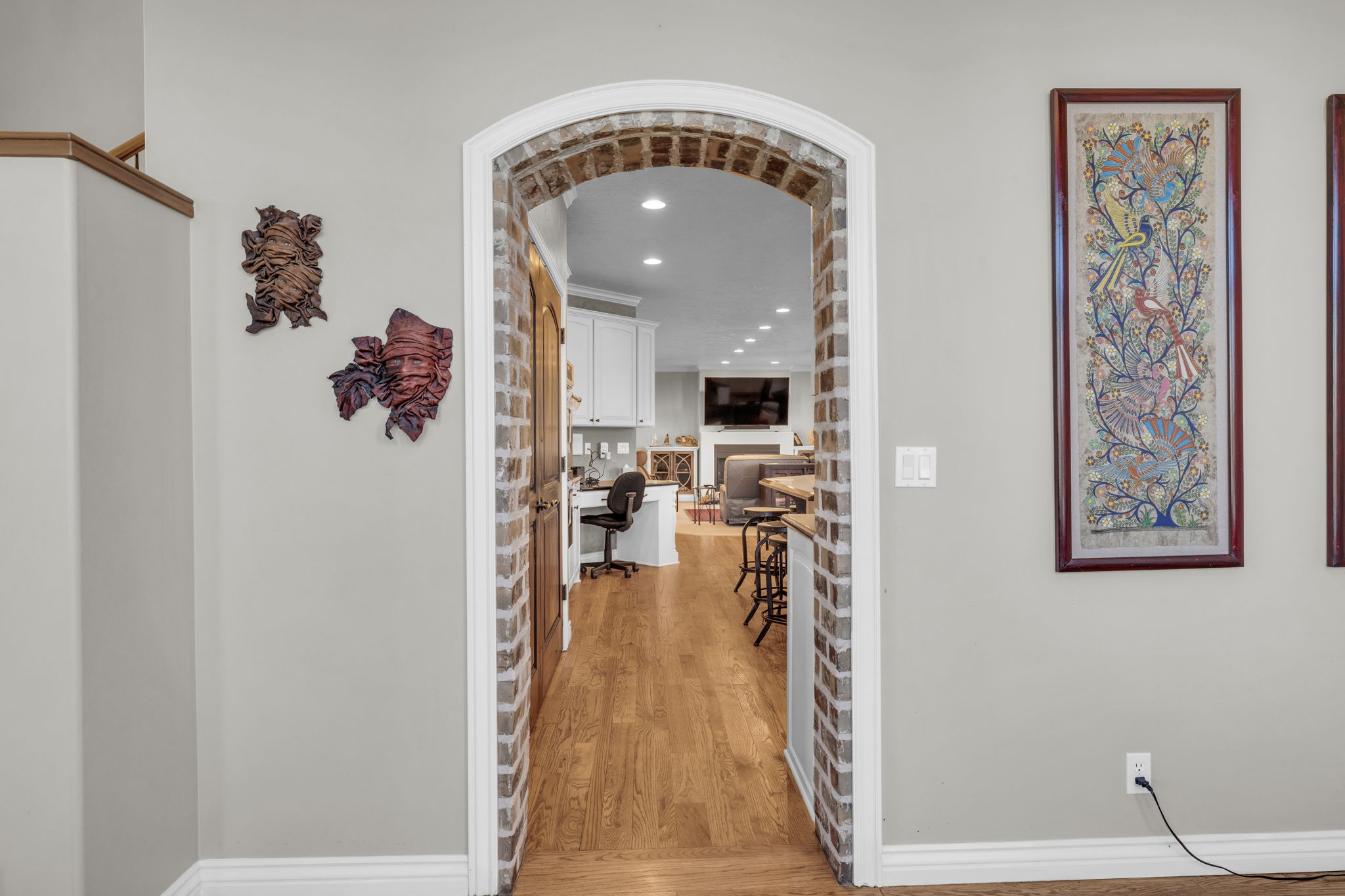 Brick-lined arched entryway featuring wood-finish flooring, white baseboards, and light neutral wall paint