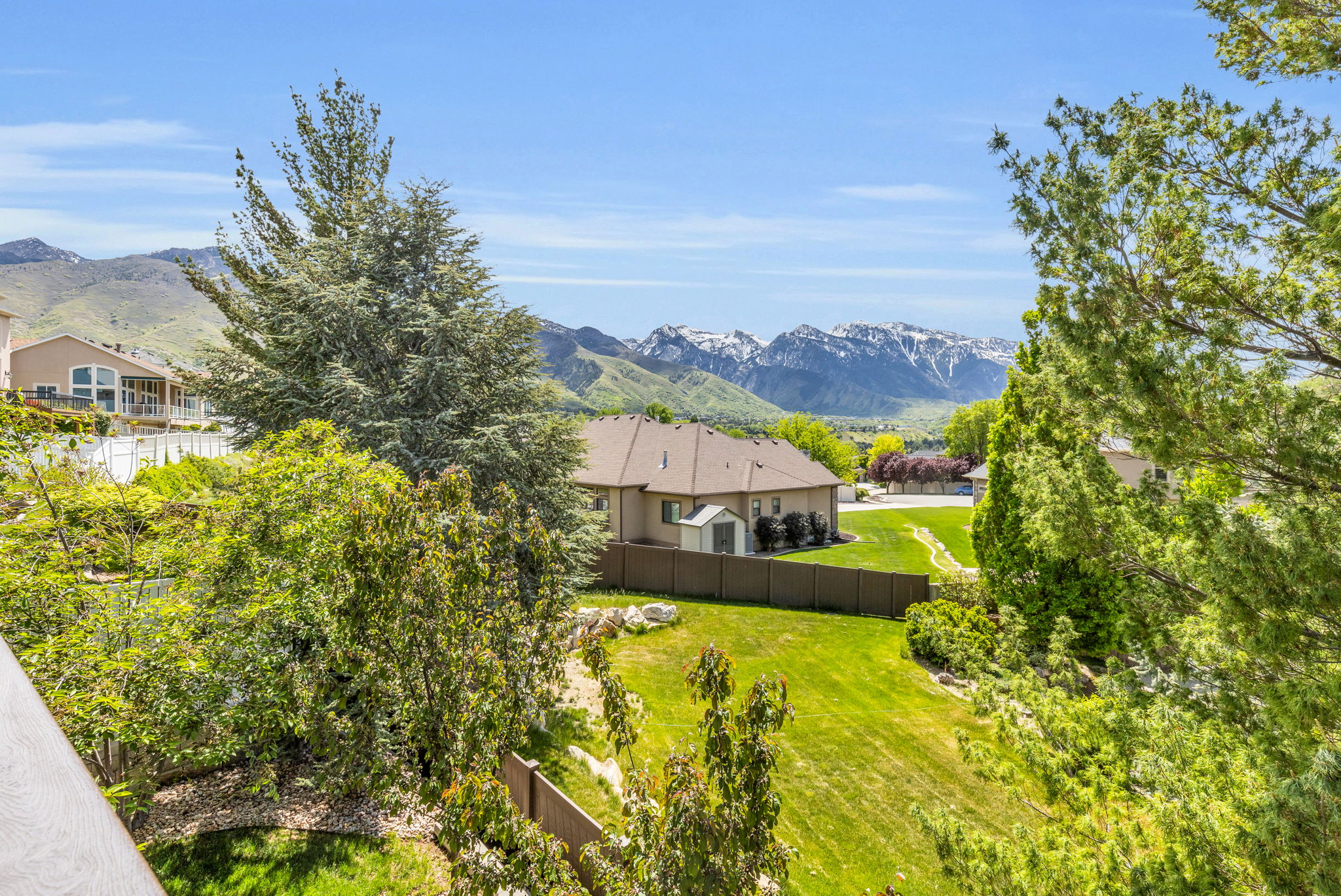 Expansive hillside property featuring a manicured lawn, established trees, and mountain scenery