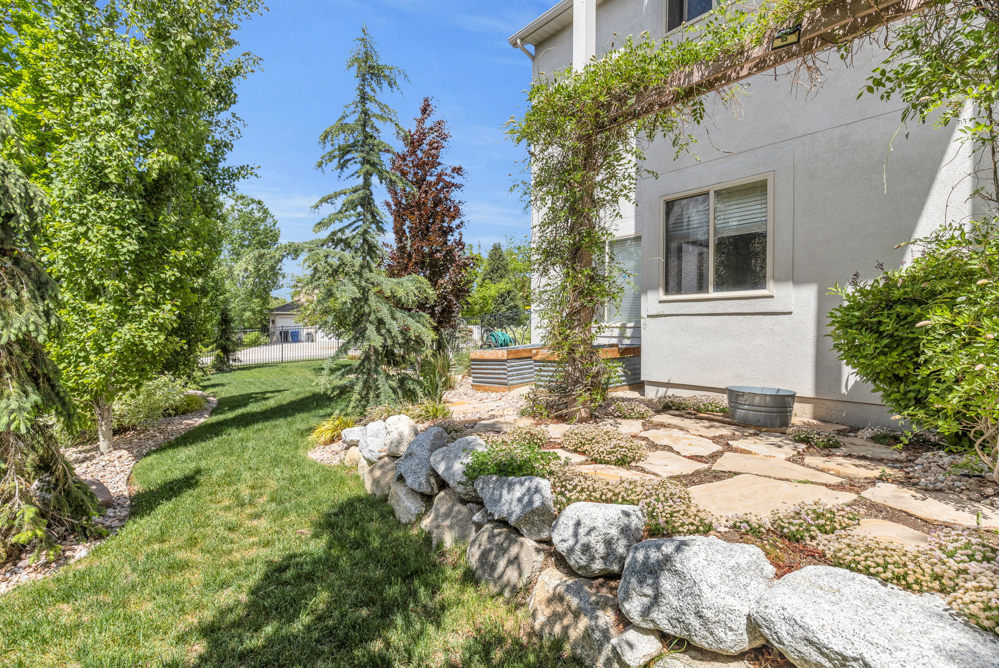 Manicured lawn area with a natural stone retaining wall and flagstone patio