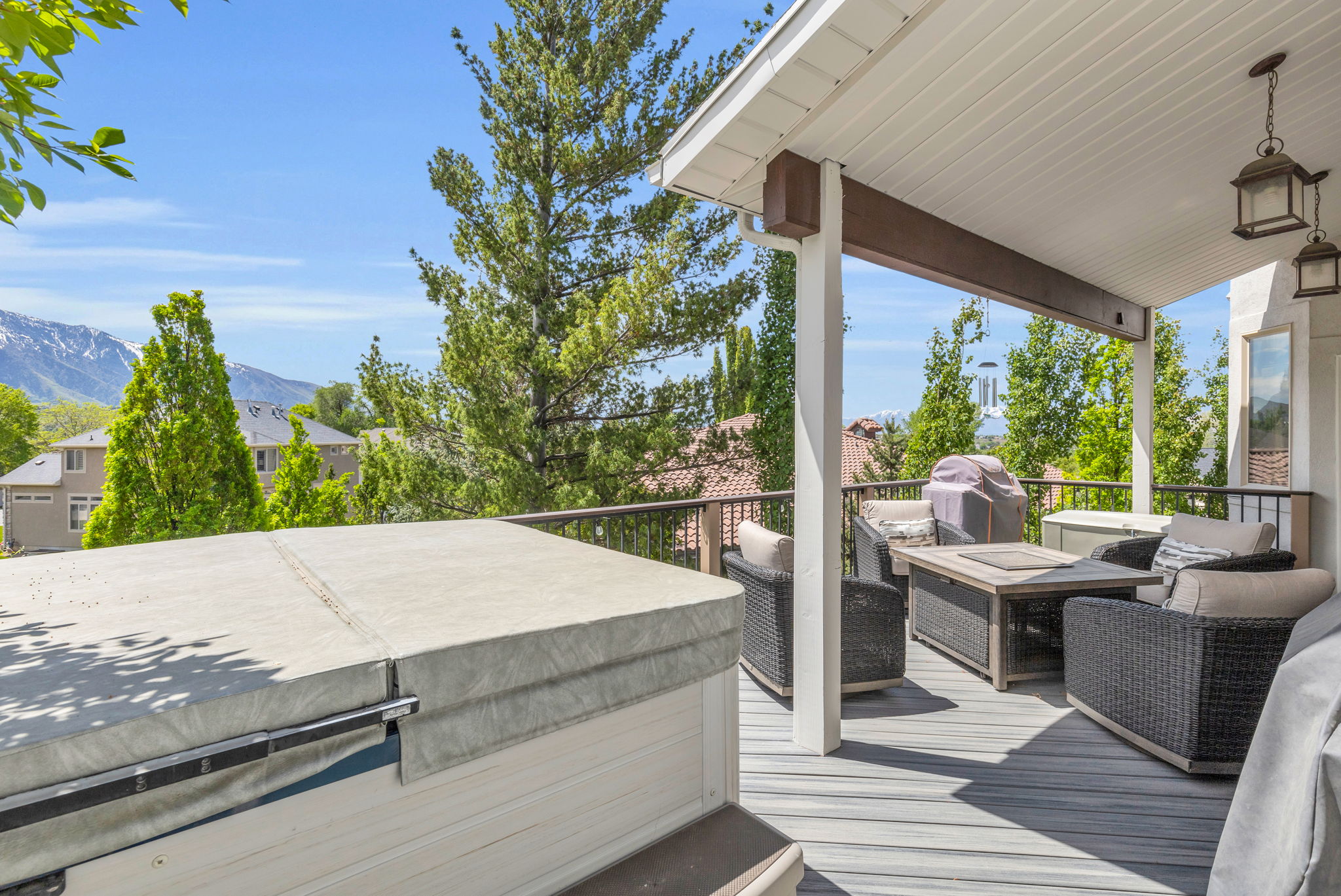 Covered outdoor deck featuring composite flooring, a privacy railing, and a built-in hot tub