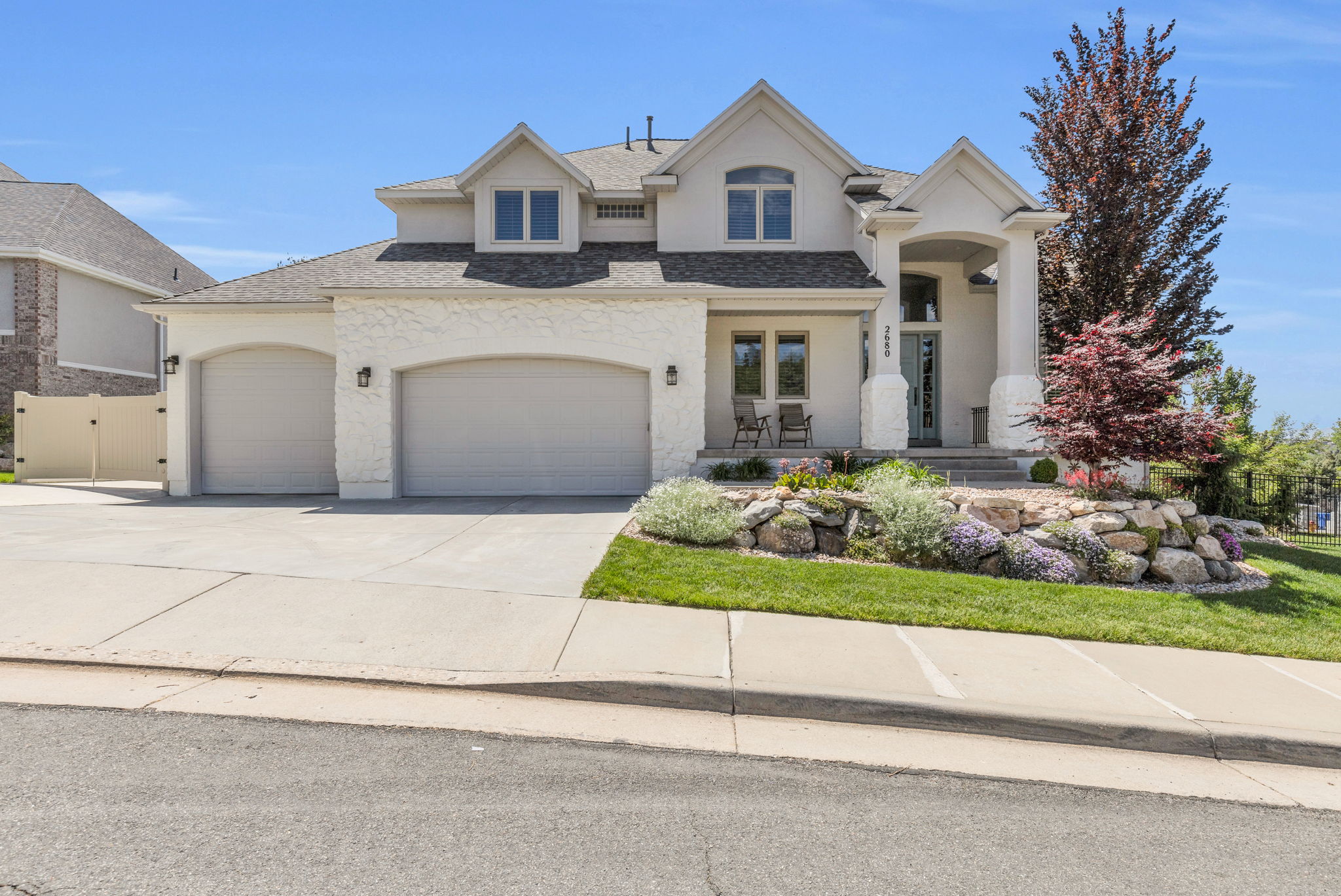 Contemporary stucco exterior featuring a portico entry and arched garage doors