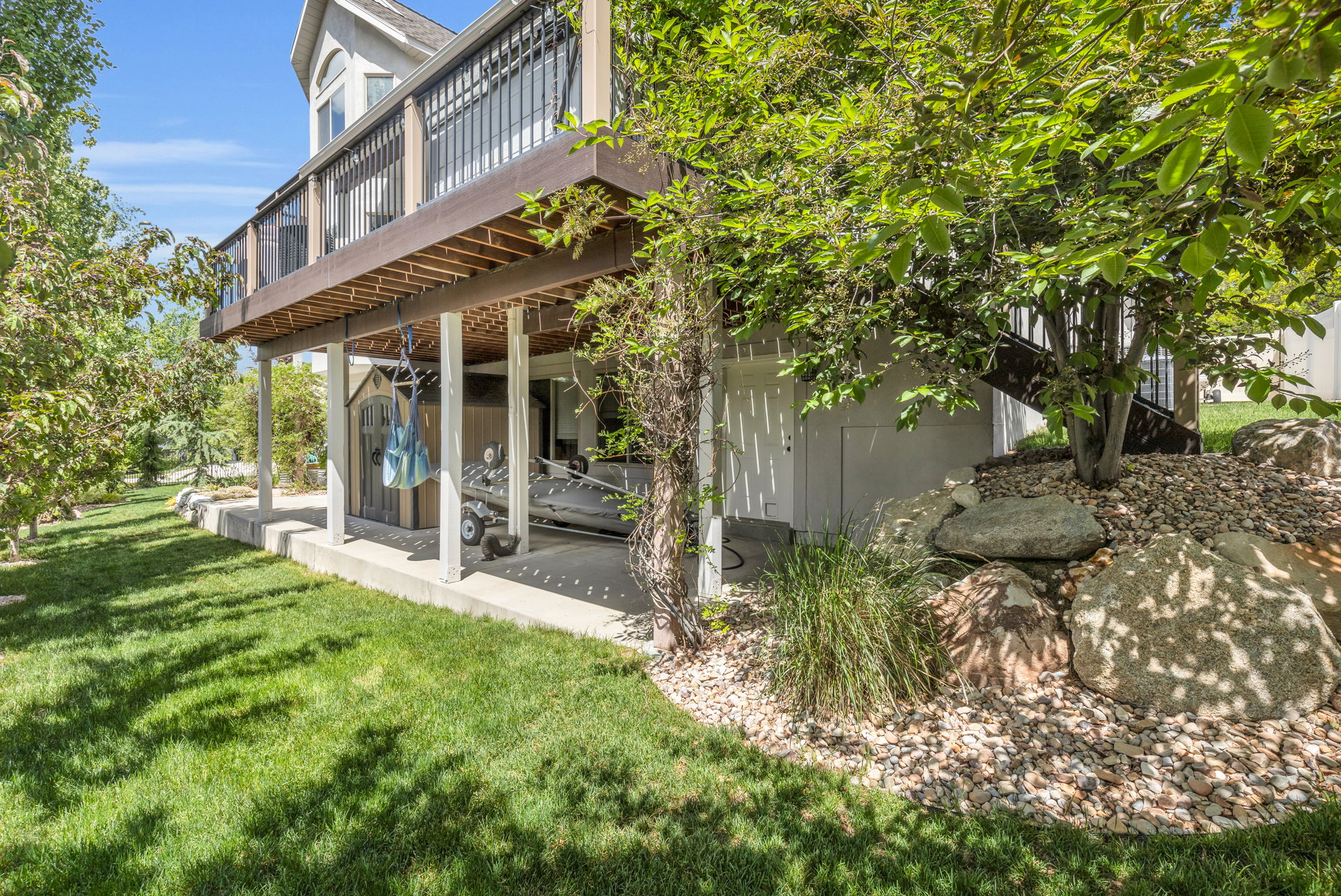 Multi-level exterior featuring a ground-level patio and an upper-level deck with black railing