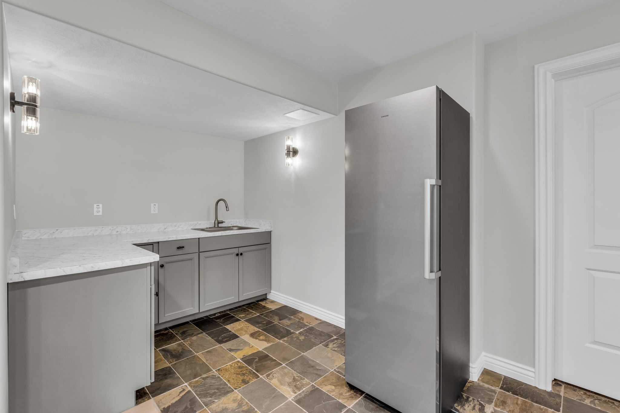 Kitchenette featuring gray shaker-style cabinetry, white quartz-finish countertops, and a stainless steel sink with a gooseneck faucet