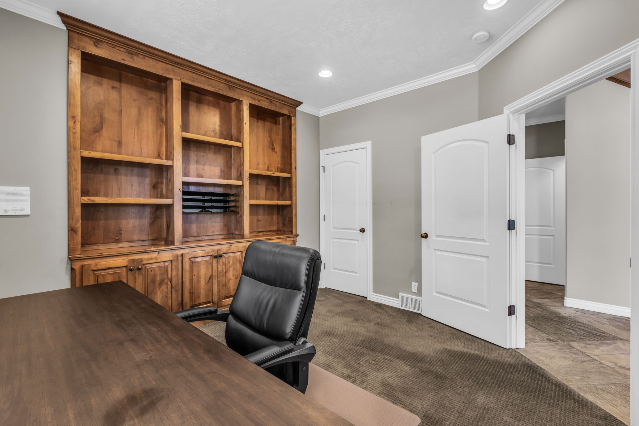 Room featuring a built-in wood cabinetry unit with shelving and lower storage, recessed ceiling lighting, and crown molding