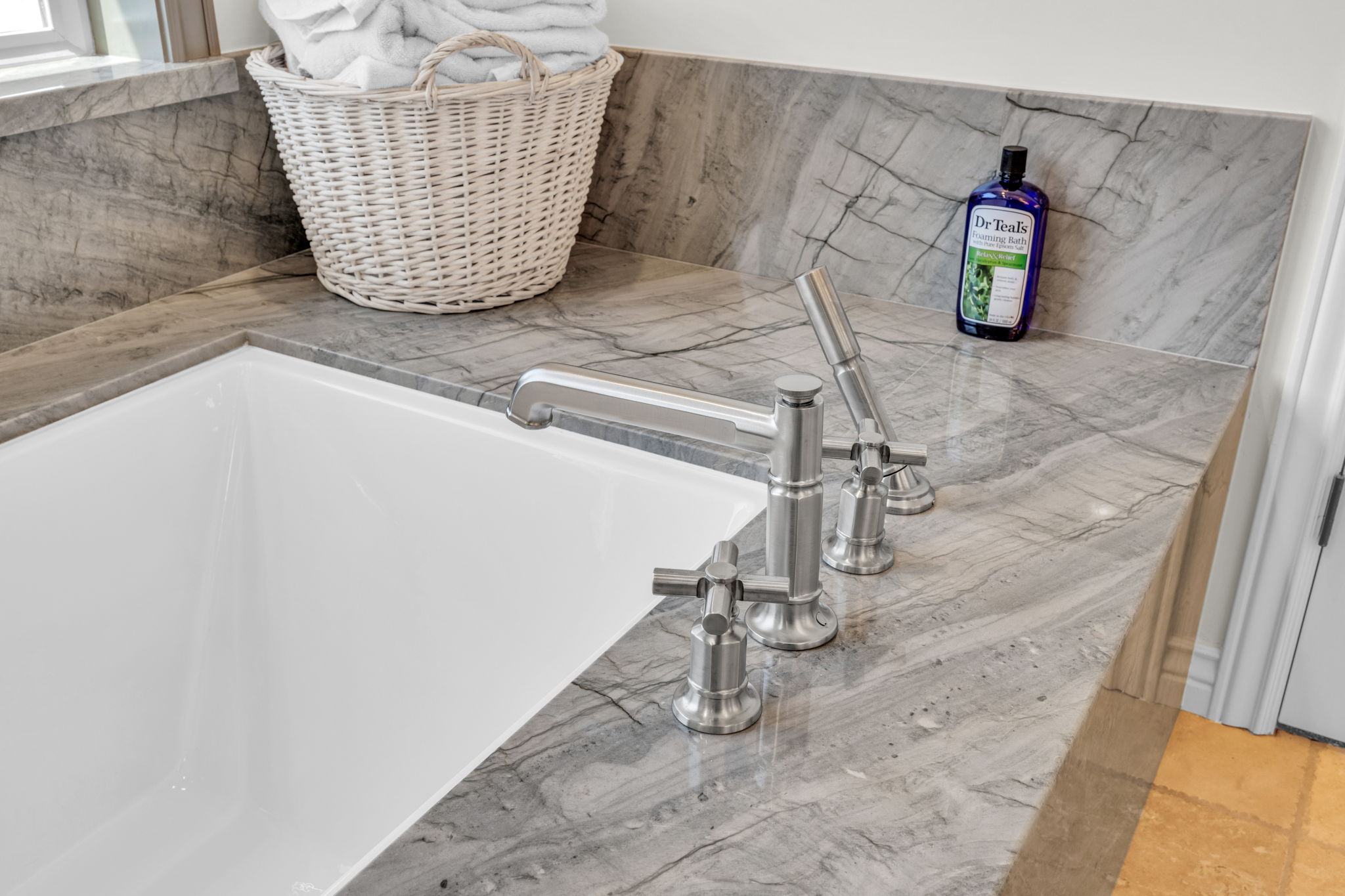Deep soaking tub with a brushed nickel Roman faucet and handheld shower sprayer