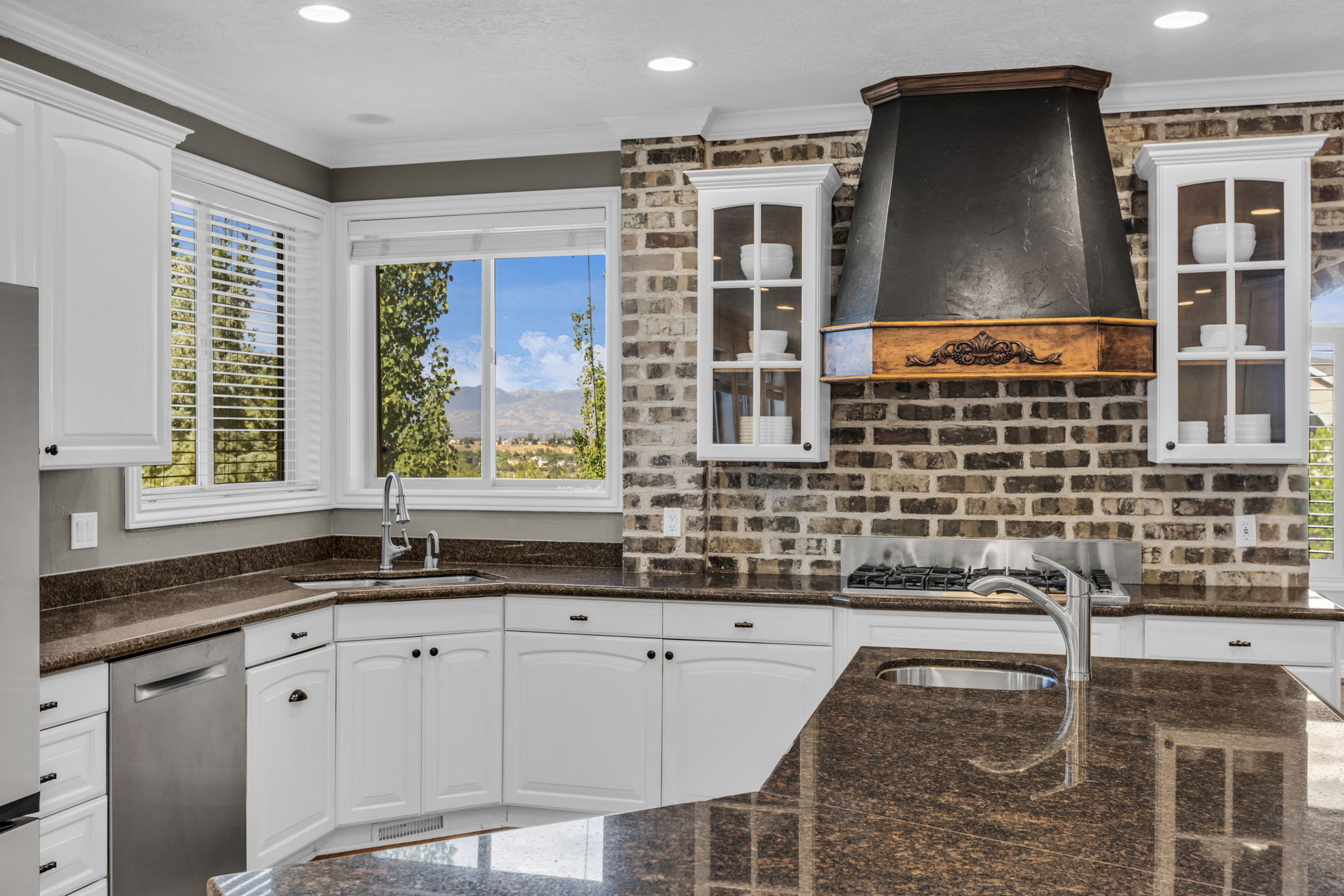 Contemporary kitchen featuring white cabinetry, dark granite countertops, and a brick-patterned backsplash