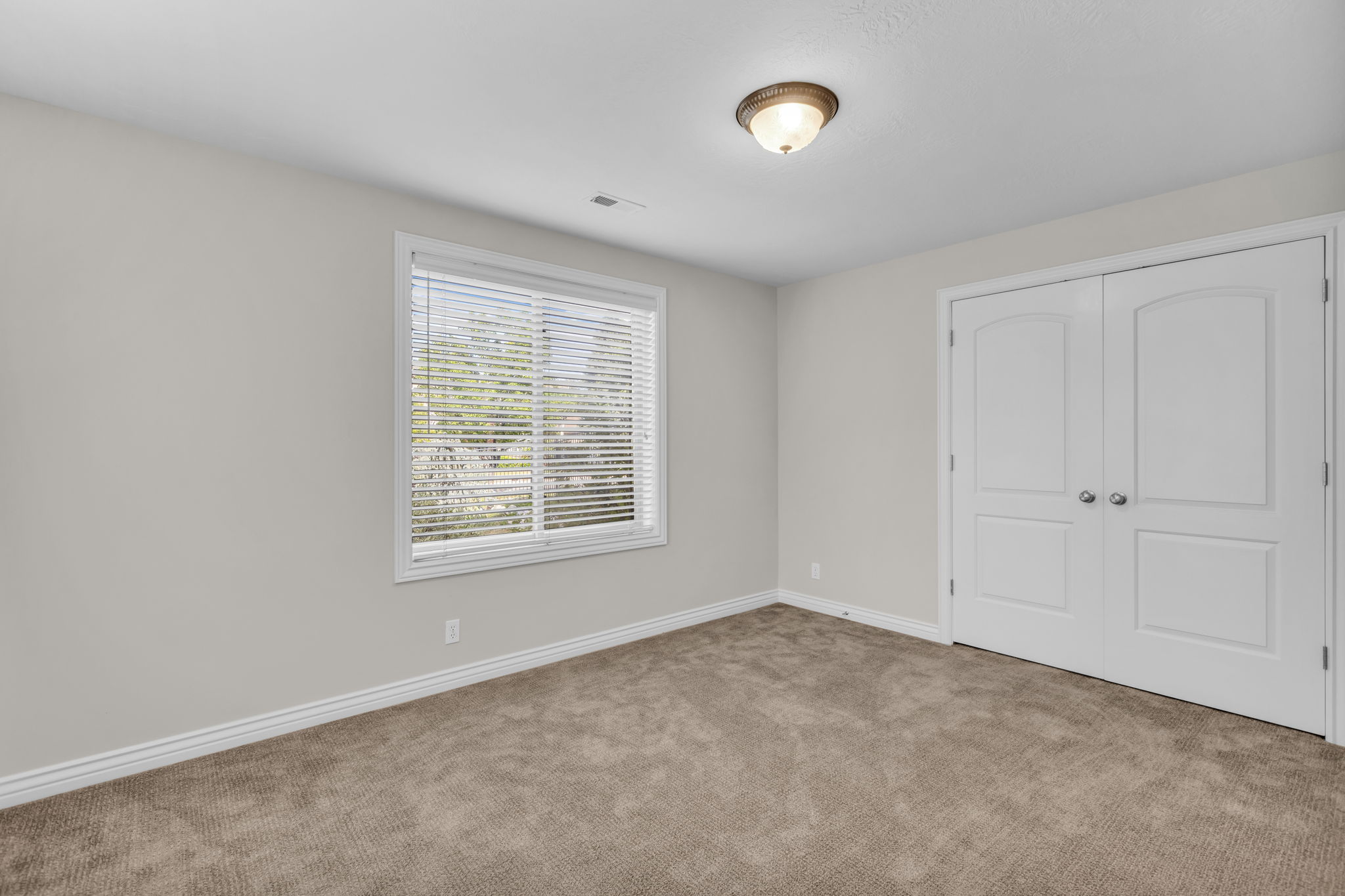 Windowed room featuring neutral wall paint, white baseboards, and brown carpet flooring