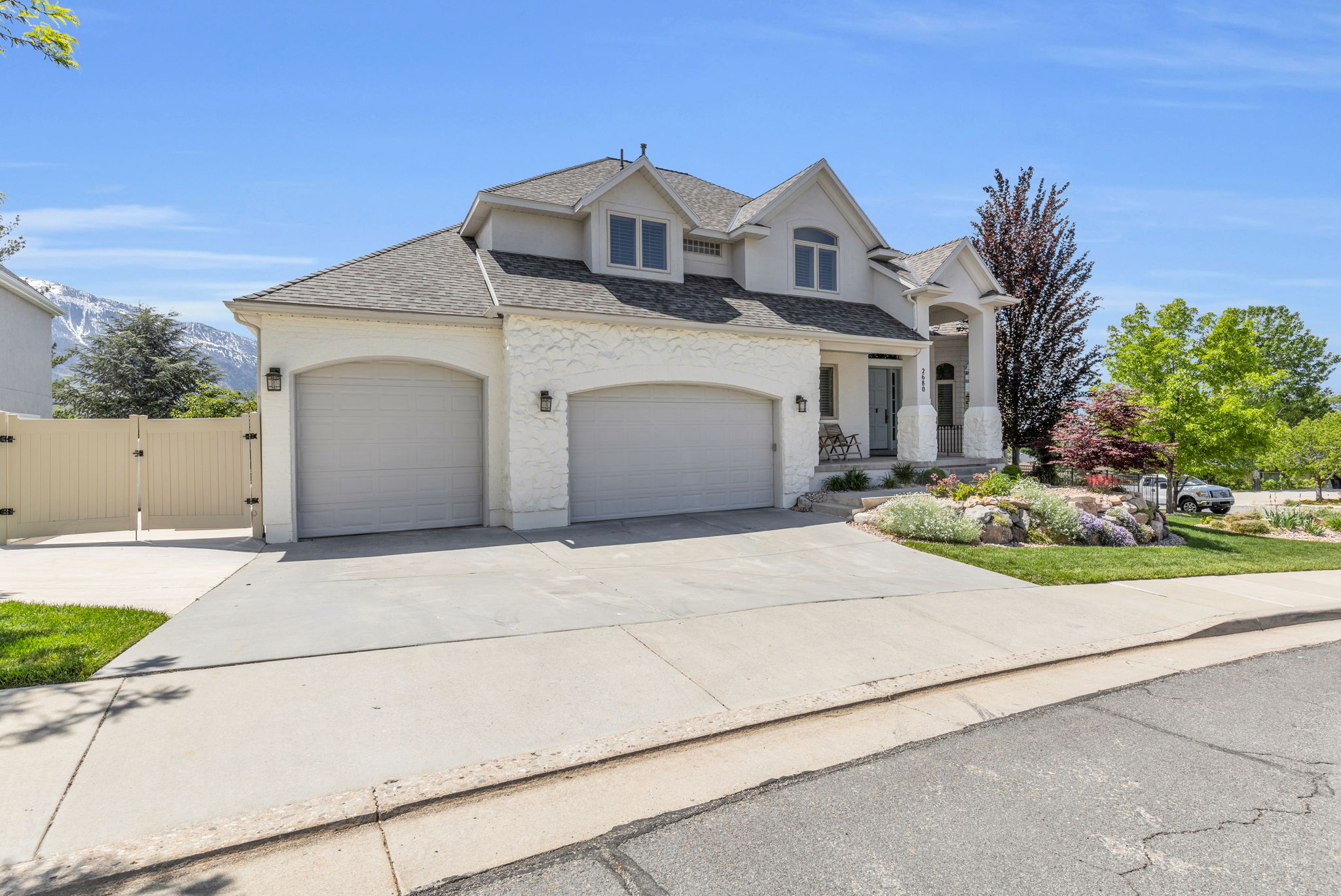 Stucco exterior with a multi-gabled roofline and two arched garage doors