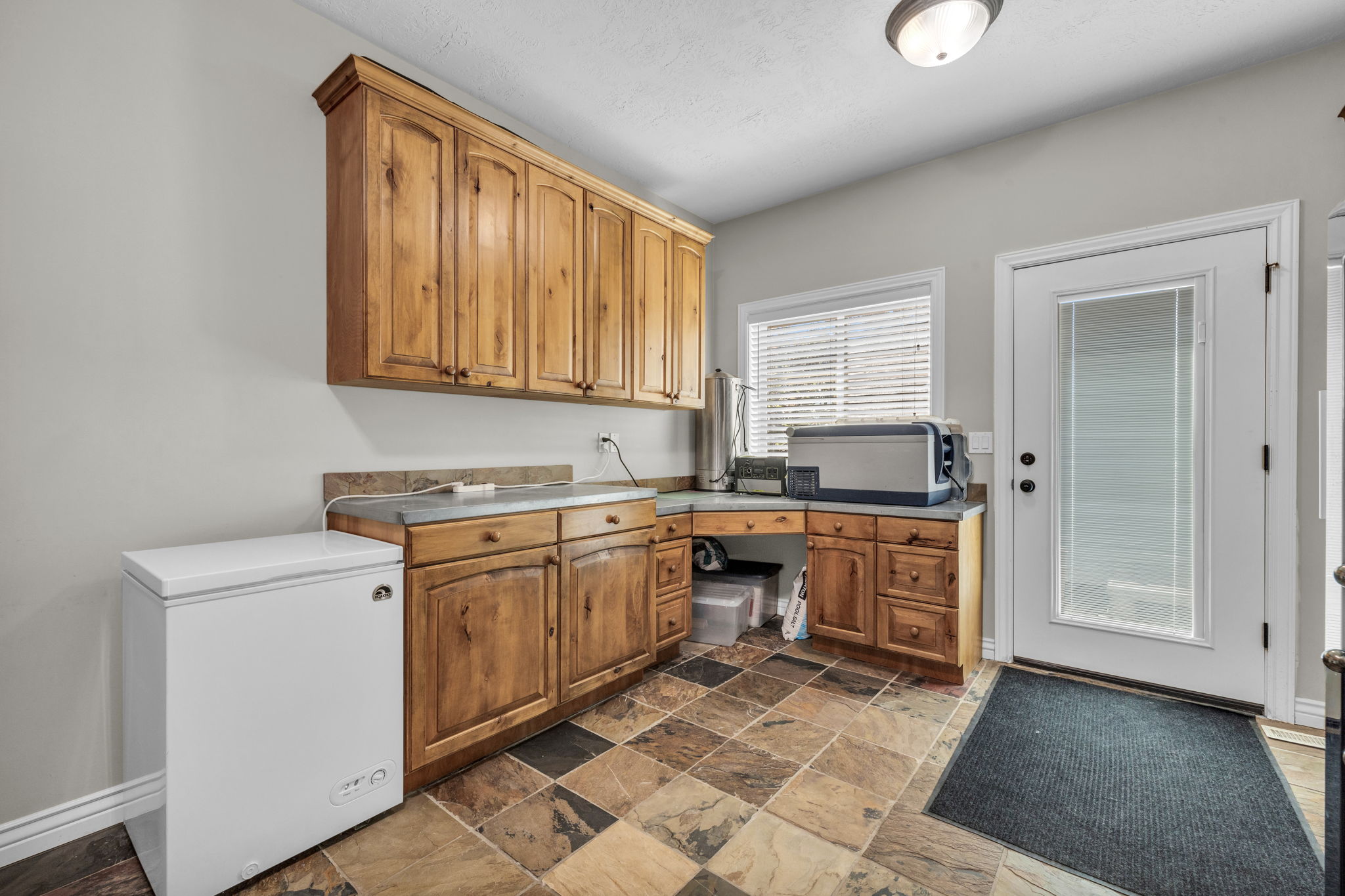 Utility area featuring wood cabinetry, stone-look tile flooring, and a built-in countertop desk