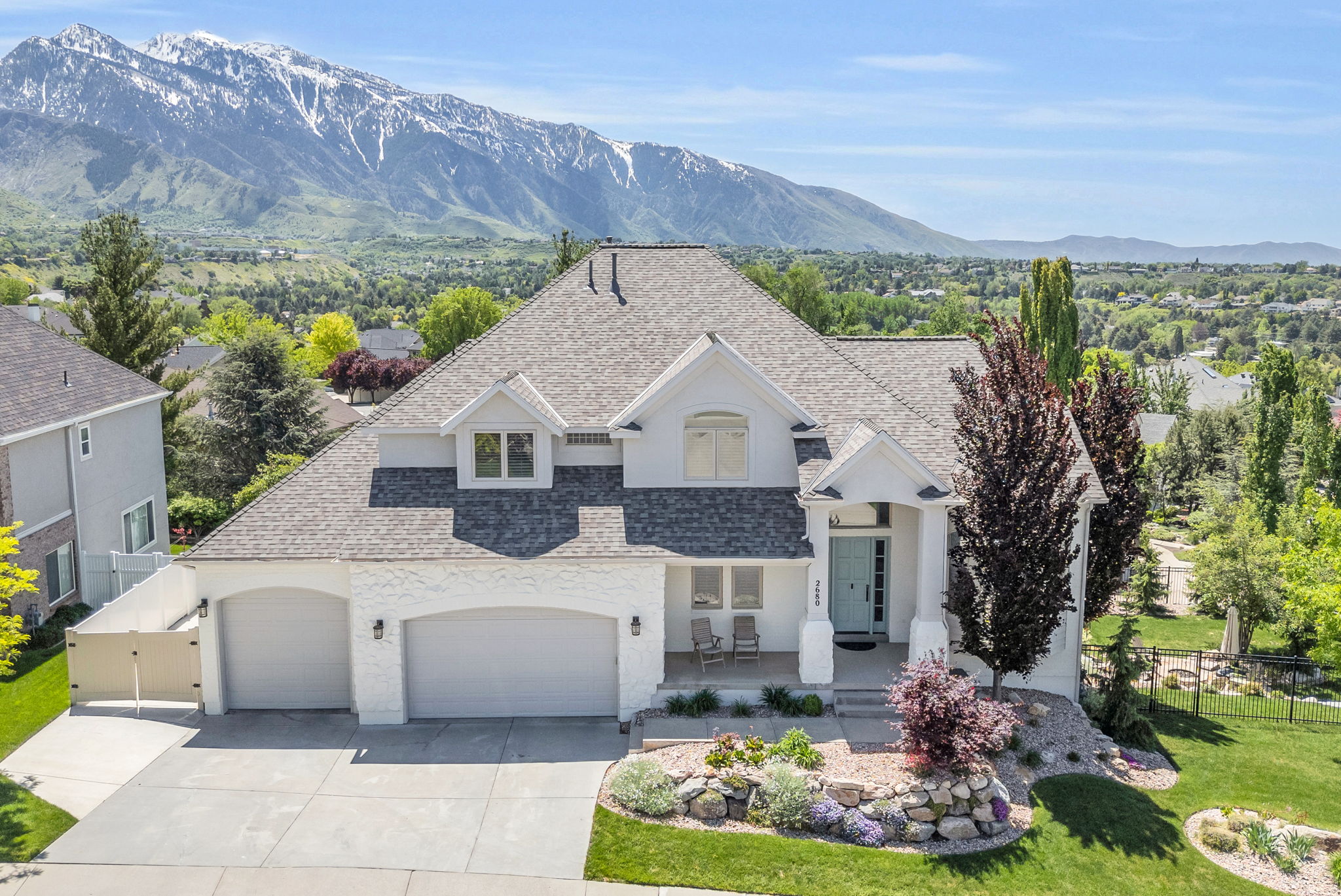 Contemporary residence featuring a two-car garage, a light blue front door, and a landscaped front yard with decorative rock and mature plantings
