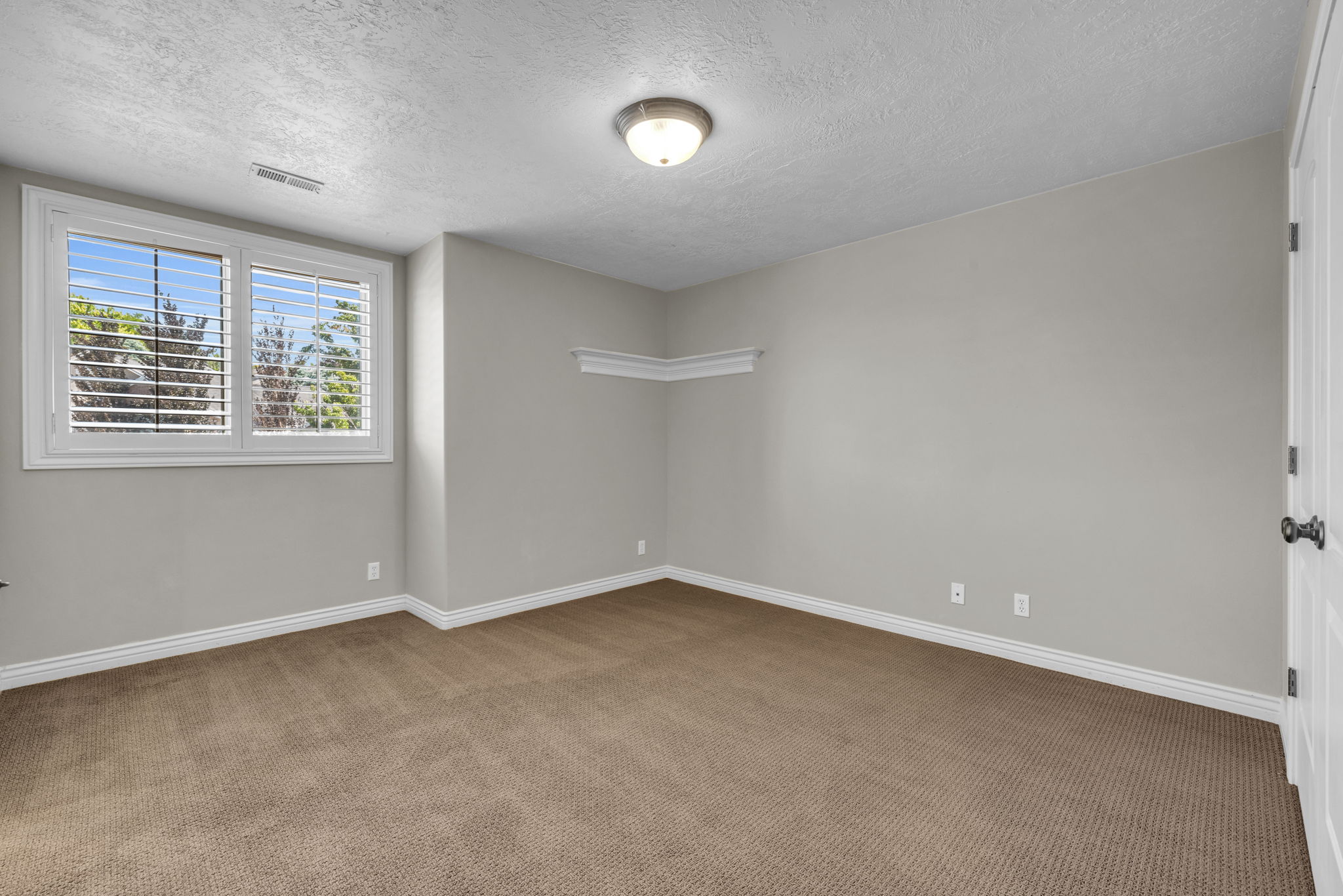 Neutral wall color with wall-to-wall carpeting and white baseboards