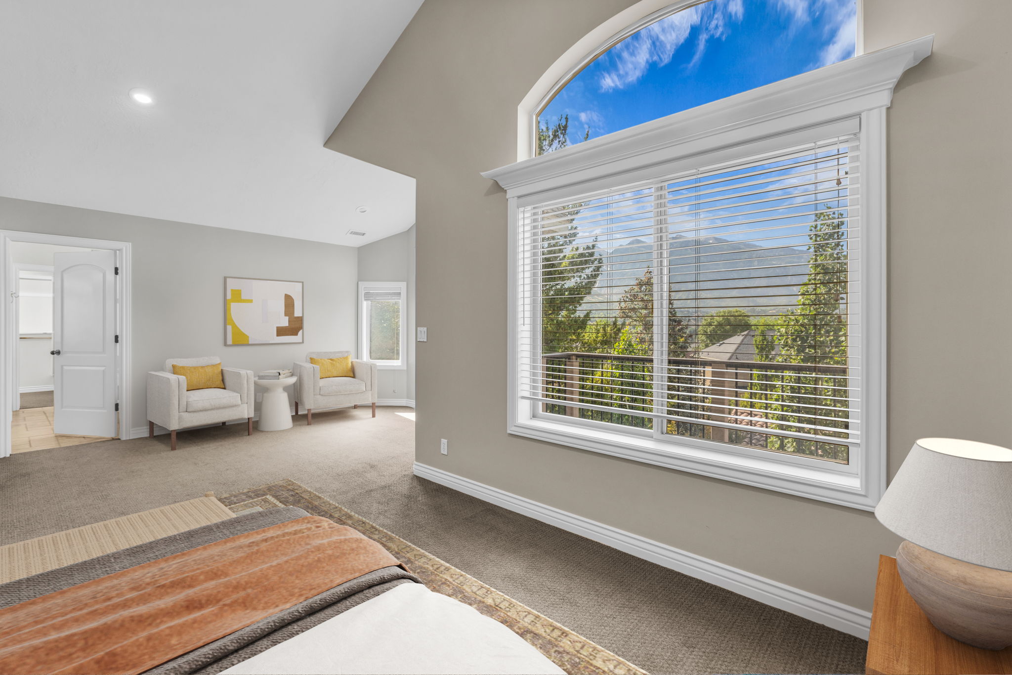 Expansive window wall with arched transom featuring white trim and horizontal blinds