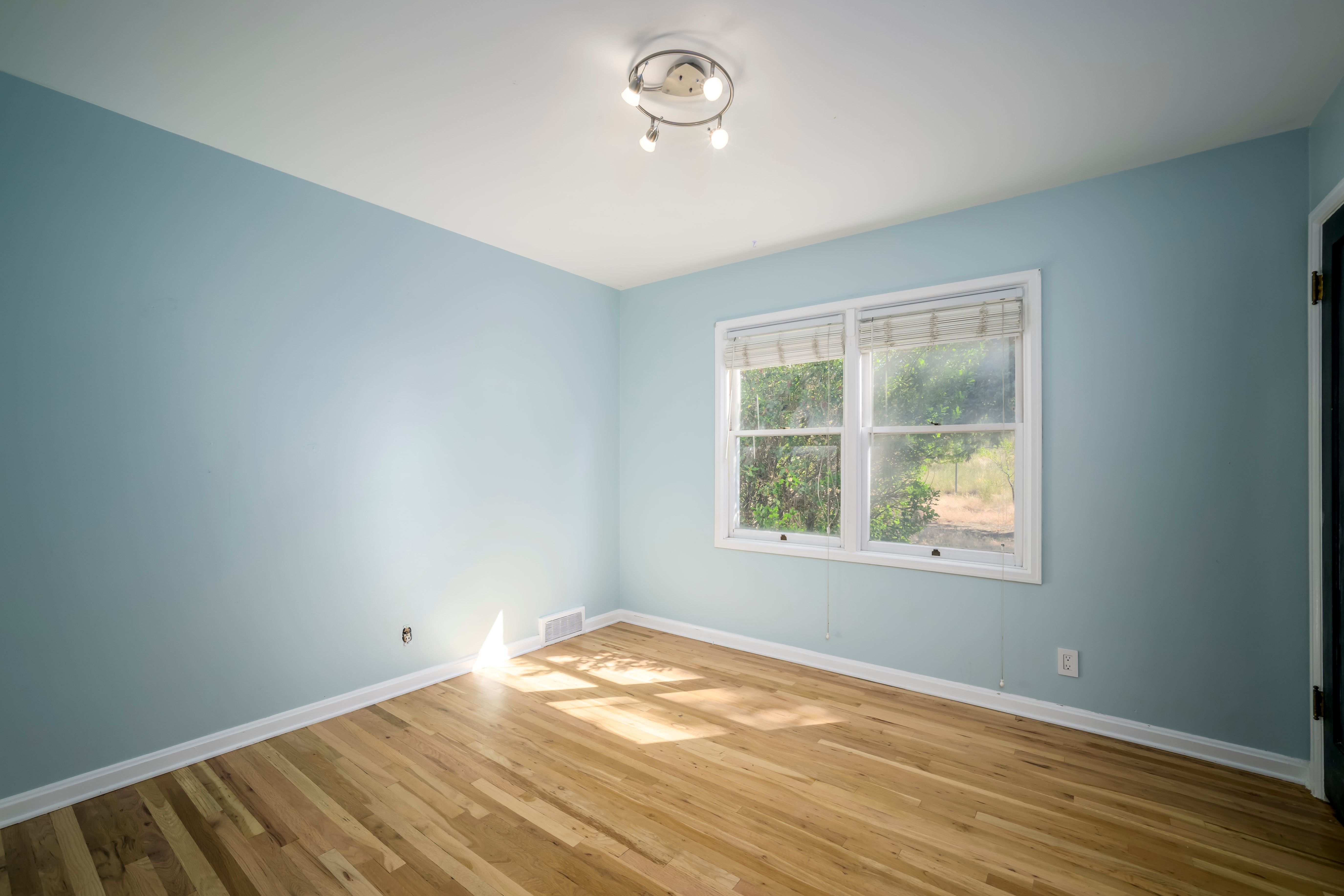 Light-filled room featuring wood-finish flooring, light blue walls, and white trim
