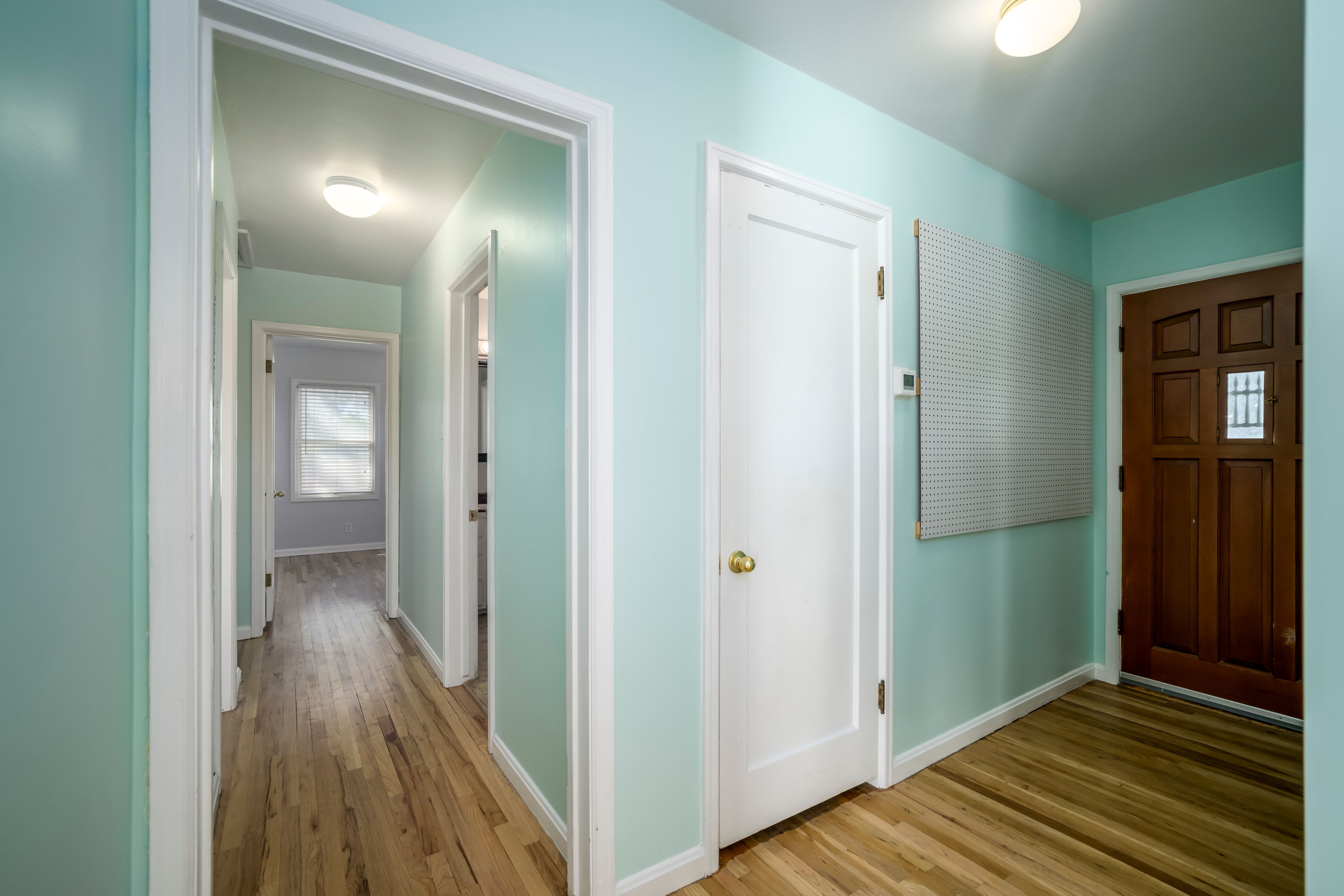 Entryway featuring a paneled wood door with decorative glass insert, wood-finish flooring, and light blue walls