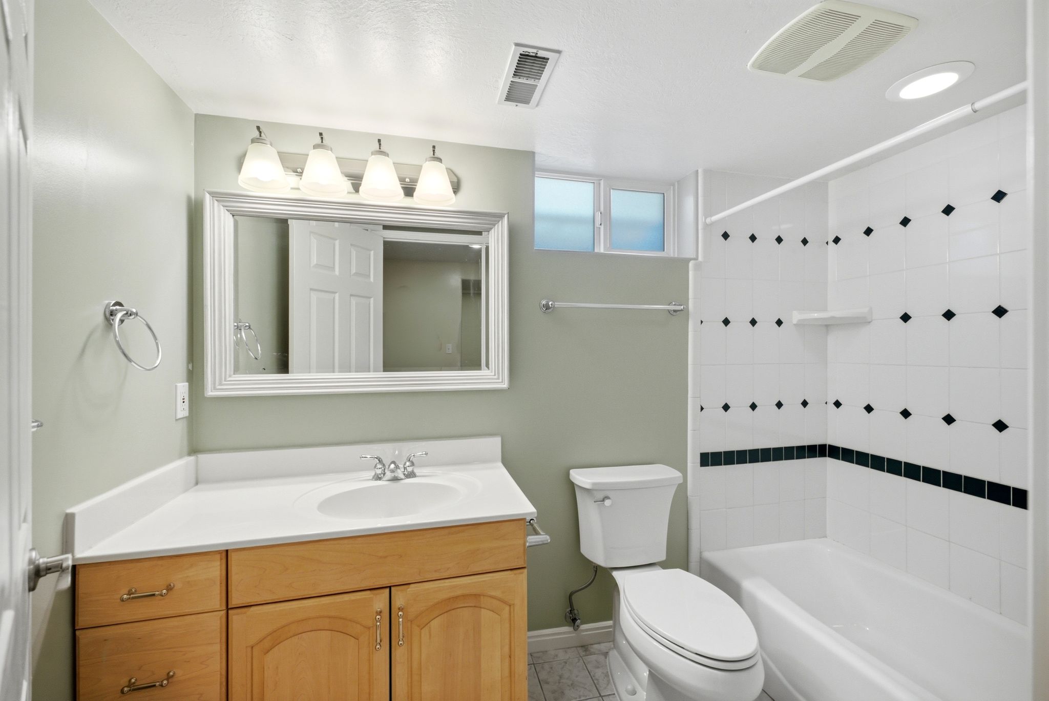 Basement Full bathroom featuring a single vanity with wood cabinetry, a white countertop, and an integrated sink
