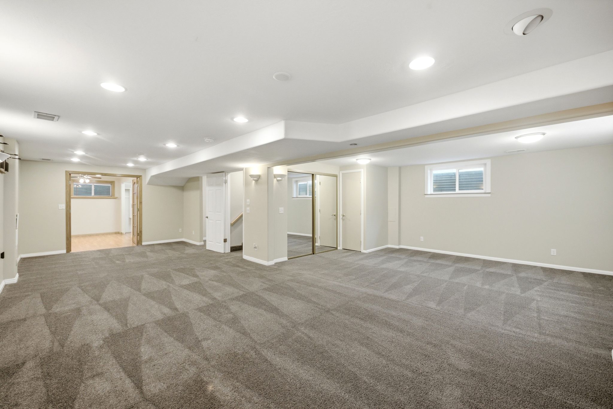 Spacious finished room featuring patterned carpeting, recessed lighting, and a neutral color palette