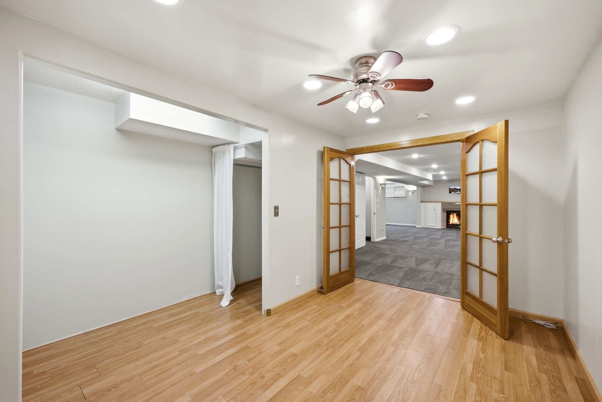 Wood-finish flooring throughout, featuring a ceiling fan with integrated lighting and recessed lighting