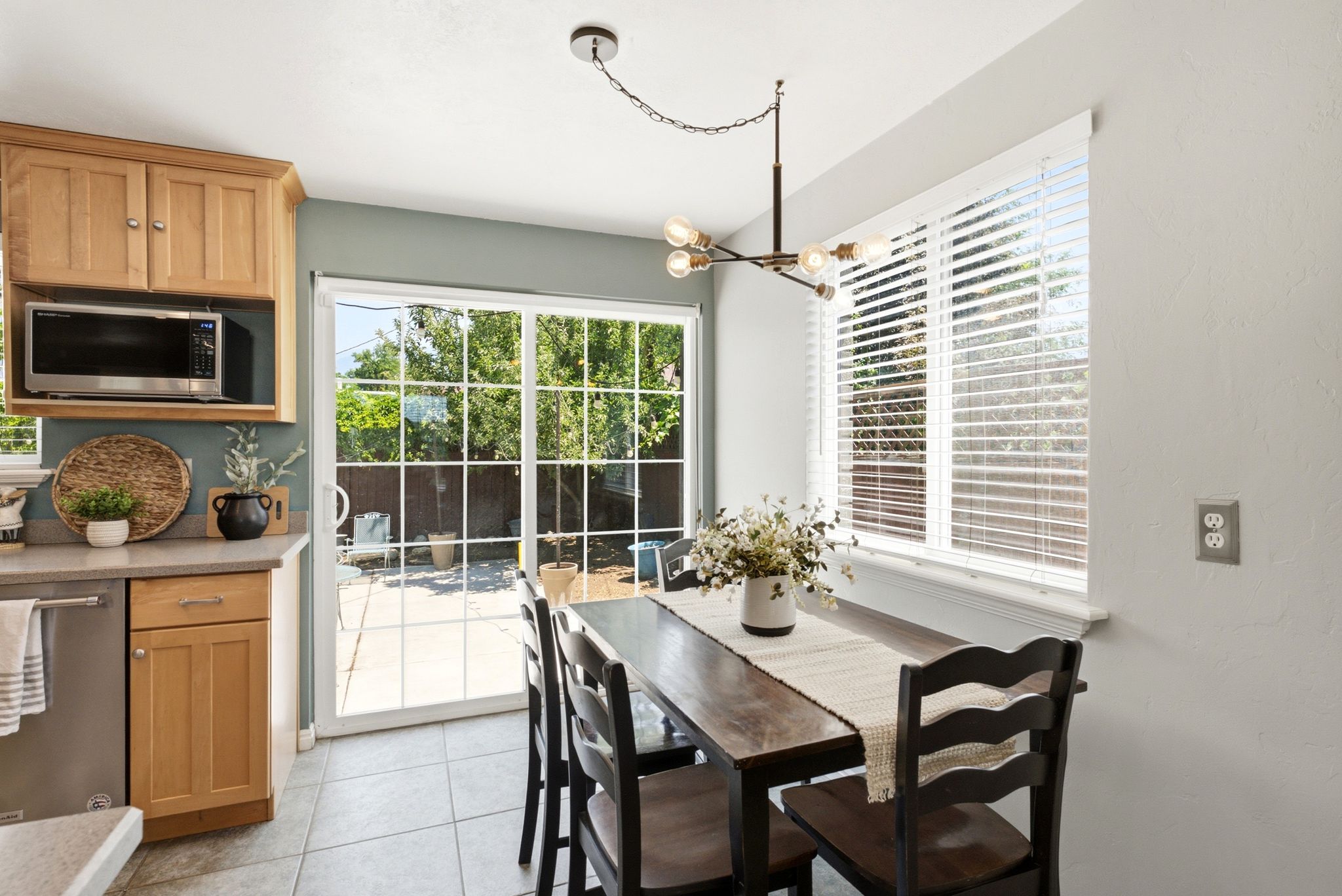 Dining area with tiled flooring, a modern chandelier, and a large window featuring blinds