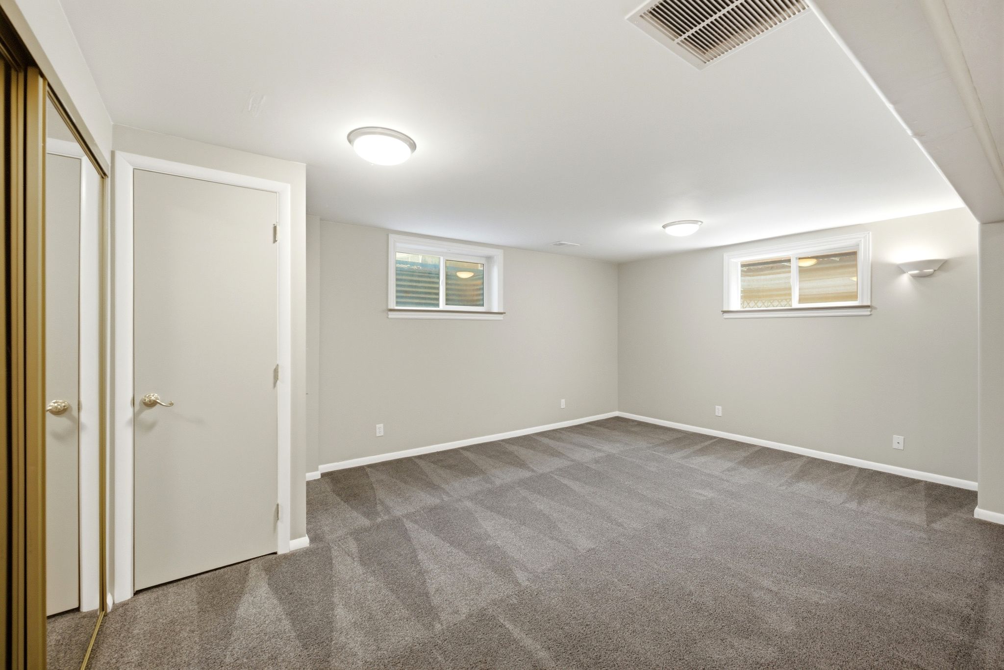 Spacious room featuring gray patterned carpet, light gray walls, and white trim