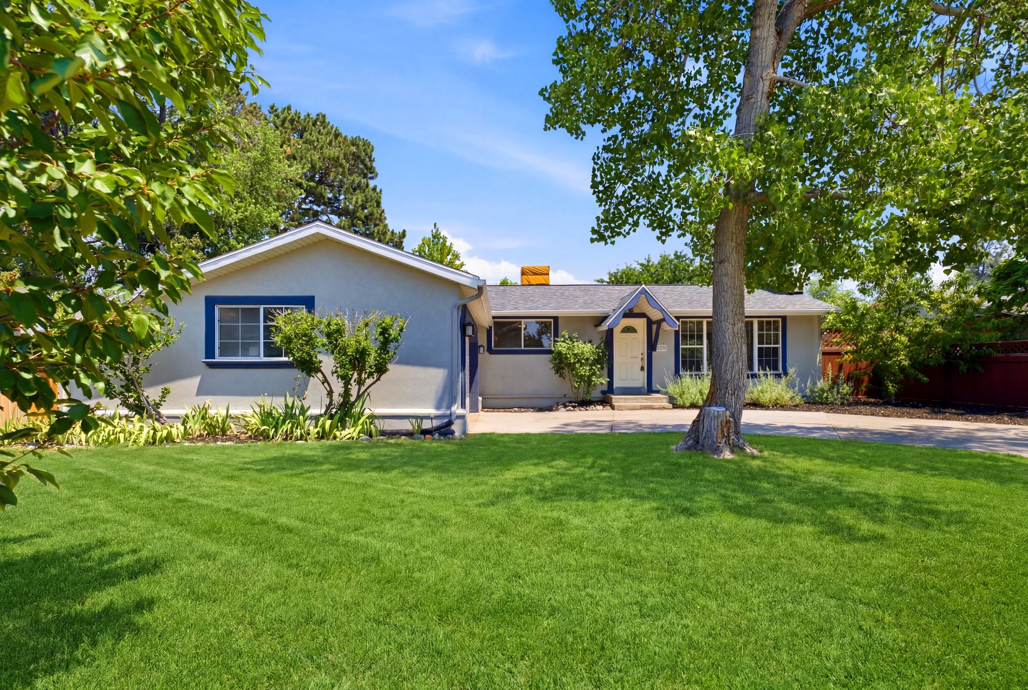 Exterior featuring a gray stucco finish, white trim, and dark blue window accents