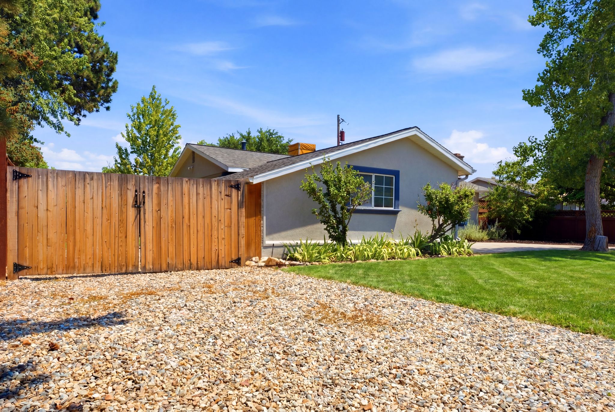 Gravel driveway leading to a wooden privacy gate with black hardware