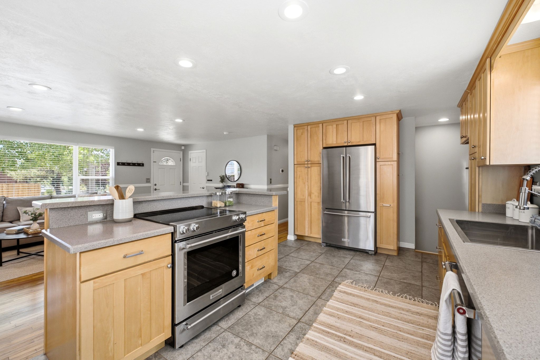 Kitchen featuring wood cabinetry, stainless steel appliances, grey stone-finish countertops, tile flooring, and recessed lighting