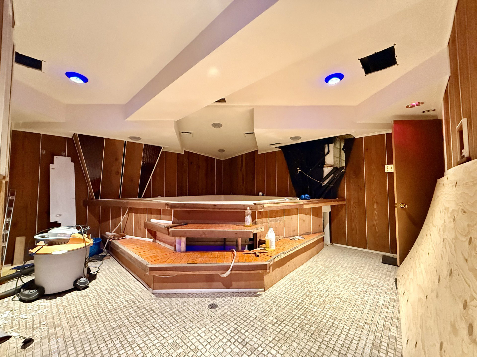 Indoor spa area featuring an elevated hot tub with integrated wooden steps