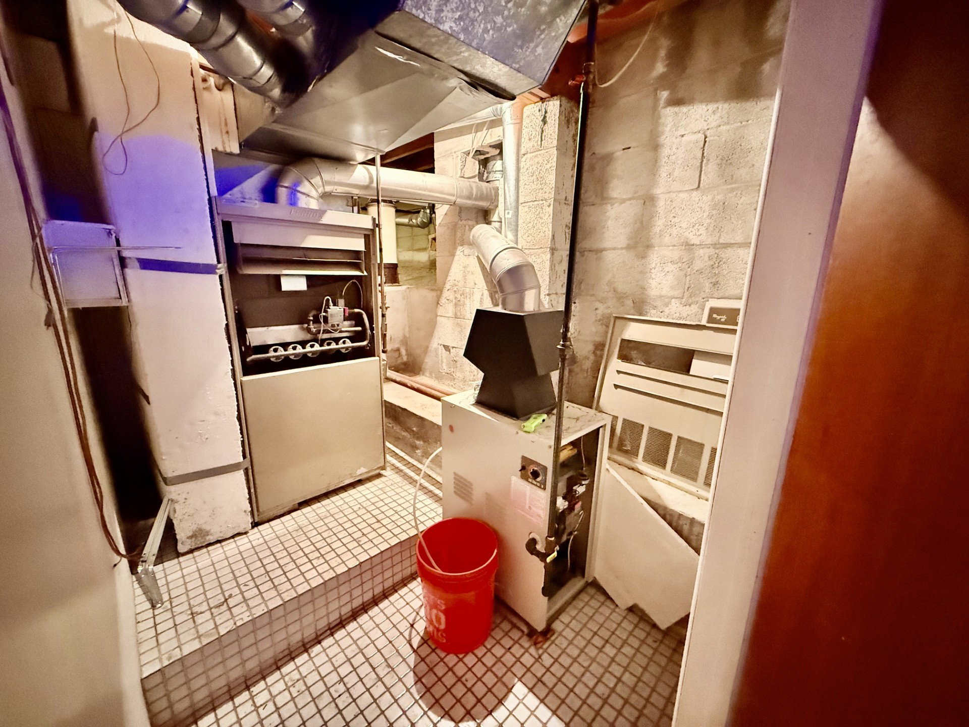 Utility room featuring a furnace system with visible internal components, associated ductwork, and tiled flooring
